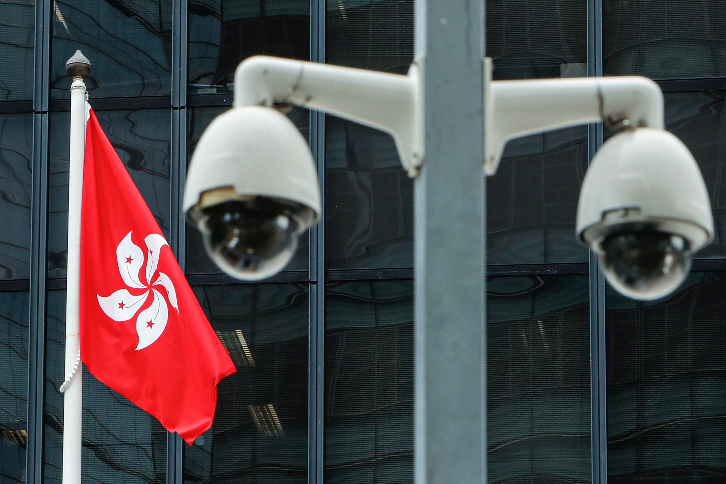 A Hong Kong flag is flown behind a pair of surveillance cameras outside the Central Government Offices in Hong Kong, China July 20, 2020. REUTERS/Tyrone Siu