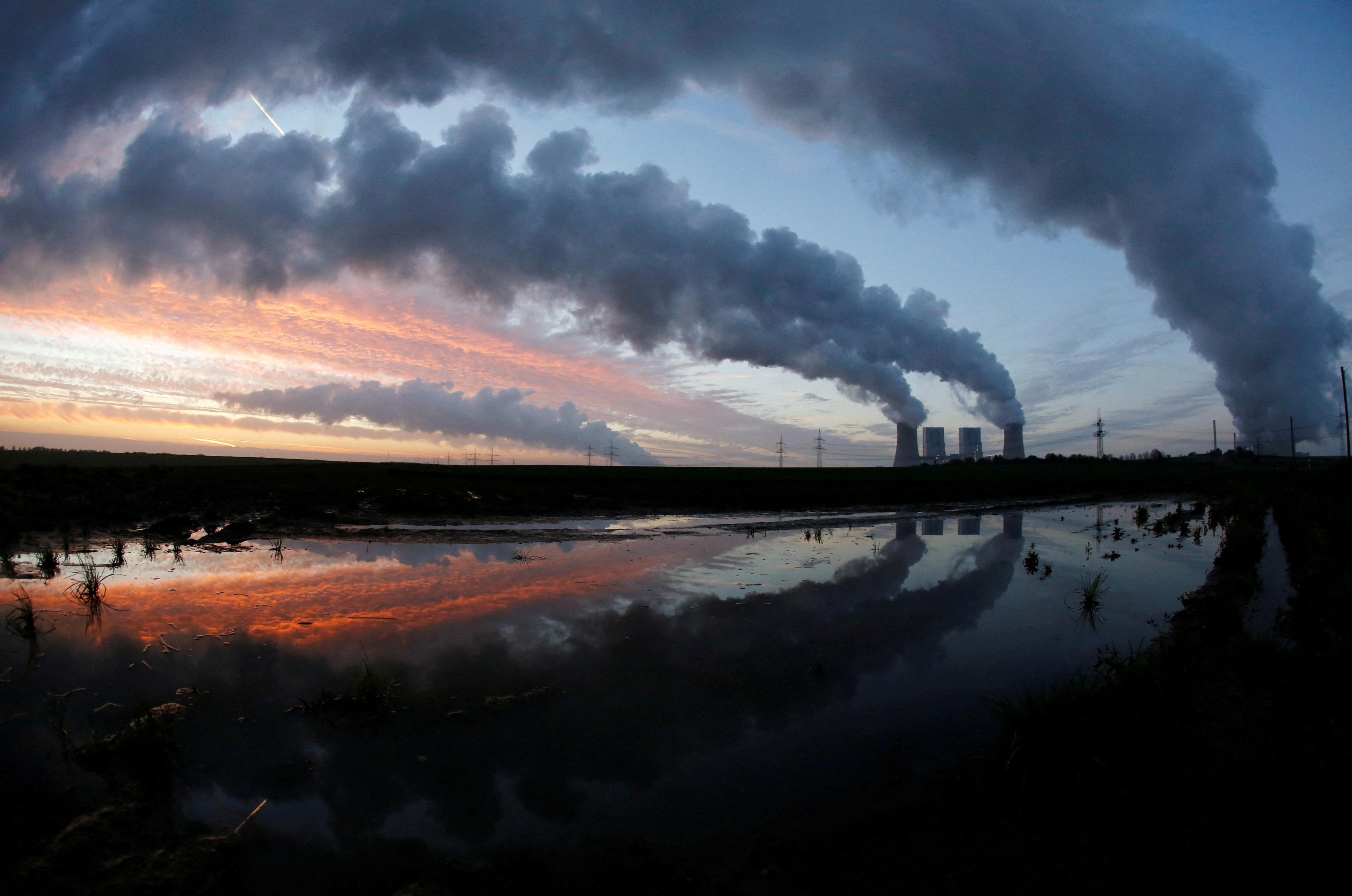 The coal power plant of German utility RWE Power is reflected in a puddle near Neurath