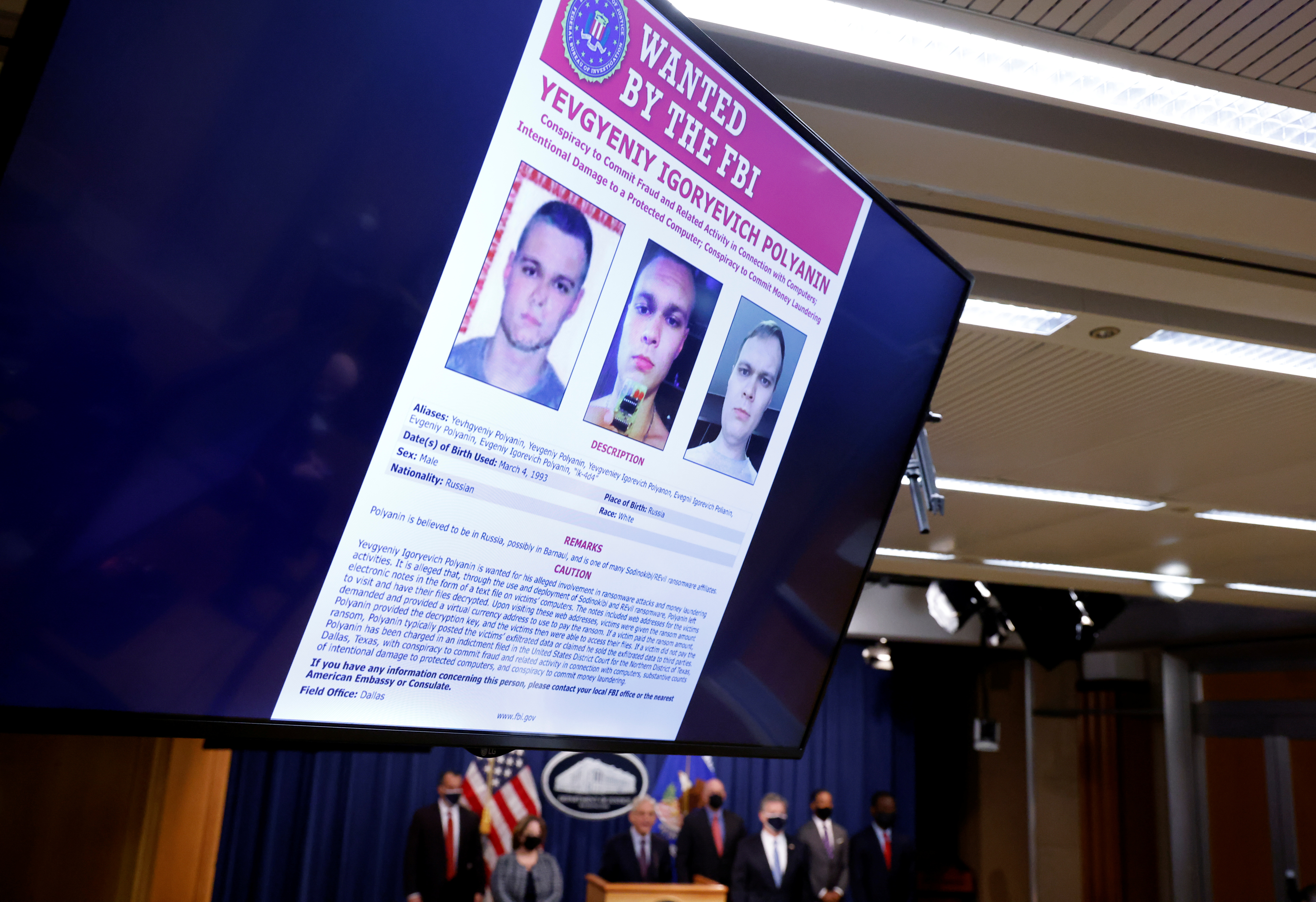 A 'wanted' poster showing Russian national Yevgeniy Polyanin is seen as U.S. Attorney General Merrick Garland announces charges over a July ransomware attack on an American company, as FBI Director Christopher Wray, Deputy Attorney General Lisa Monaco and Deputy Treasury Secretary Wally Adeyemo standby during a news conference at the Justice Department in Washington, U.S., November 8, 2021. REUTERS/Jonathan Ernst