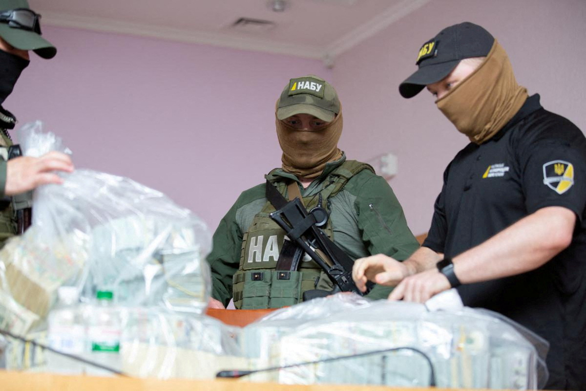 Officers stand next to plastic bags filled with U.S. Dollar banknotes seized by the National Anti-Corruption Bureau of Ukraine, in Kiev