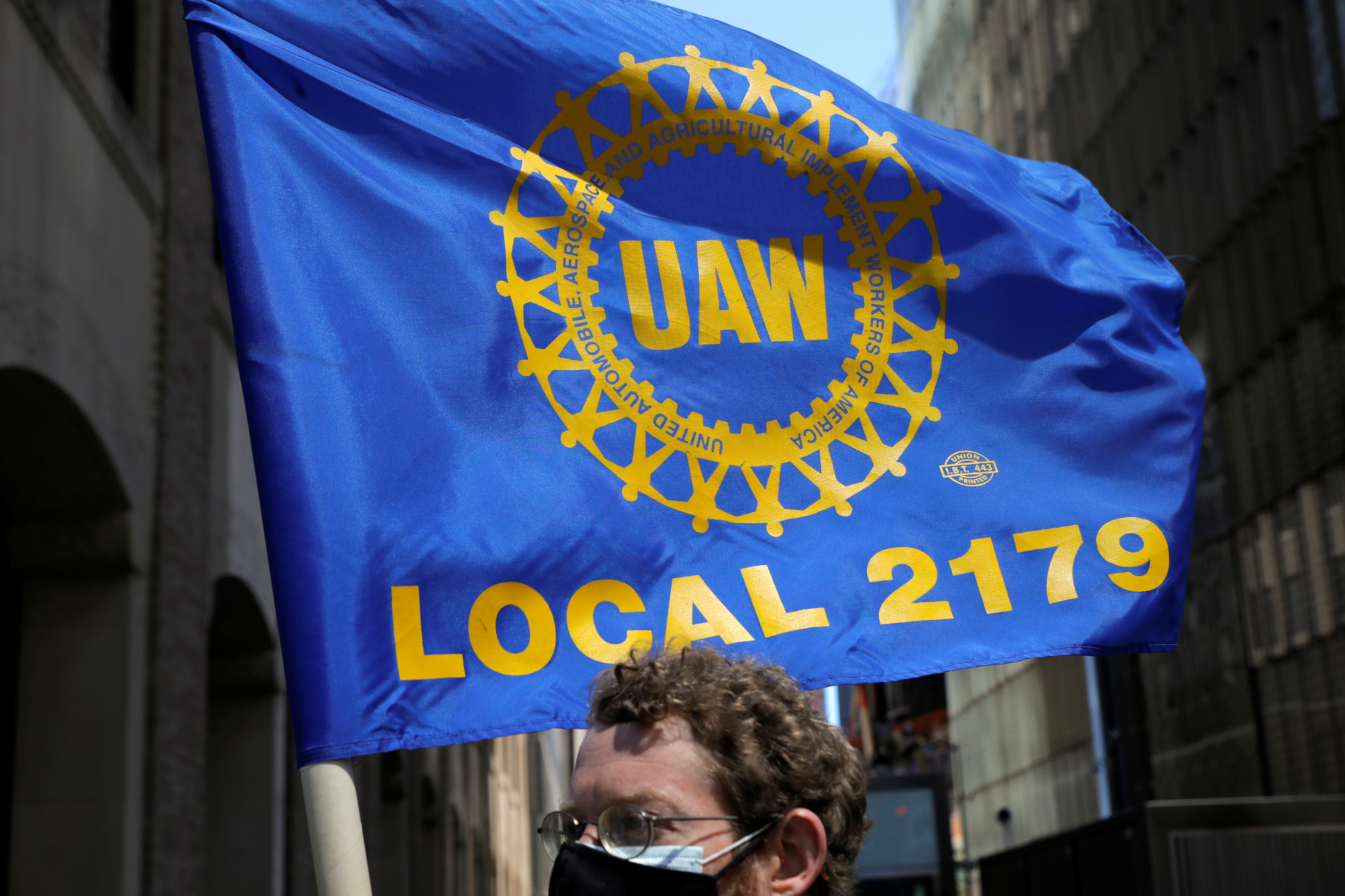 A person carries a flag with the patch from the United Auto Workers (UAW) labor union during a May Day rally for media workers held by The NewsGuild of New York on International Workers' Day in Manhattan, New York City, New York, U.S., May 1, 2021. REUTERS/Andrew Kelly