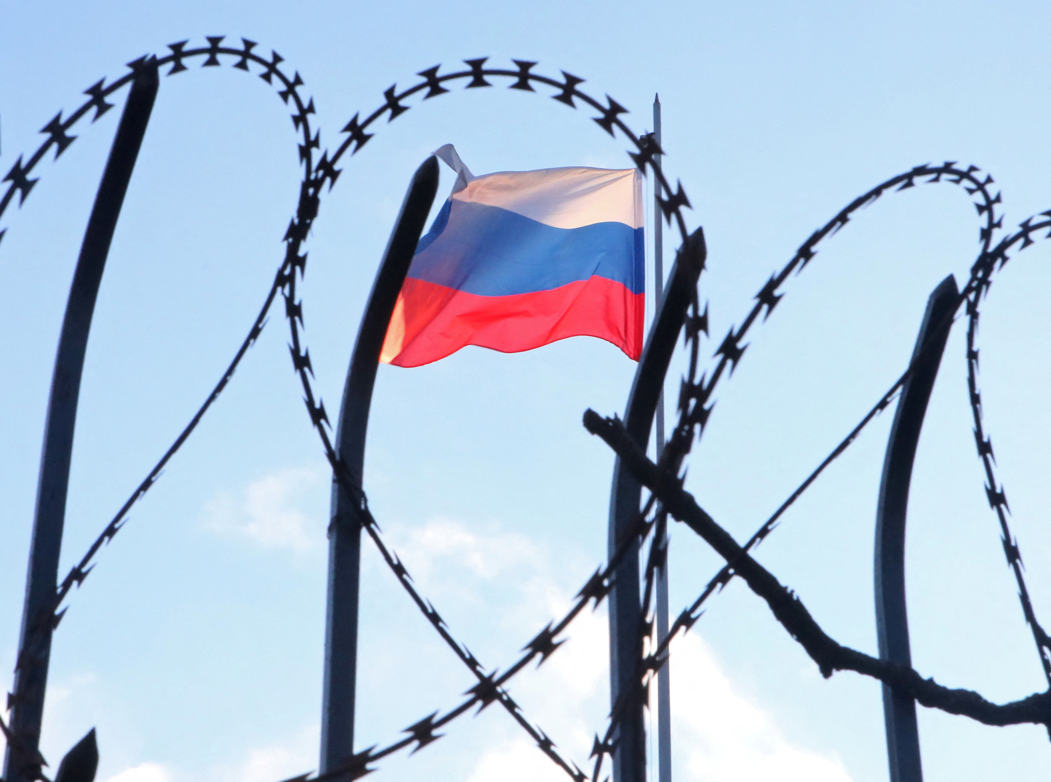 The Russian flag is seen behind a razor wire fence on the roof of the Russian Consulate General in Kharkiv