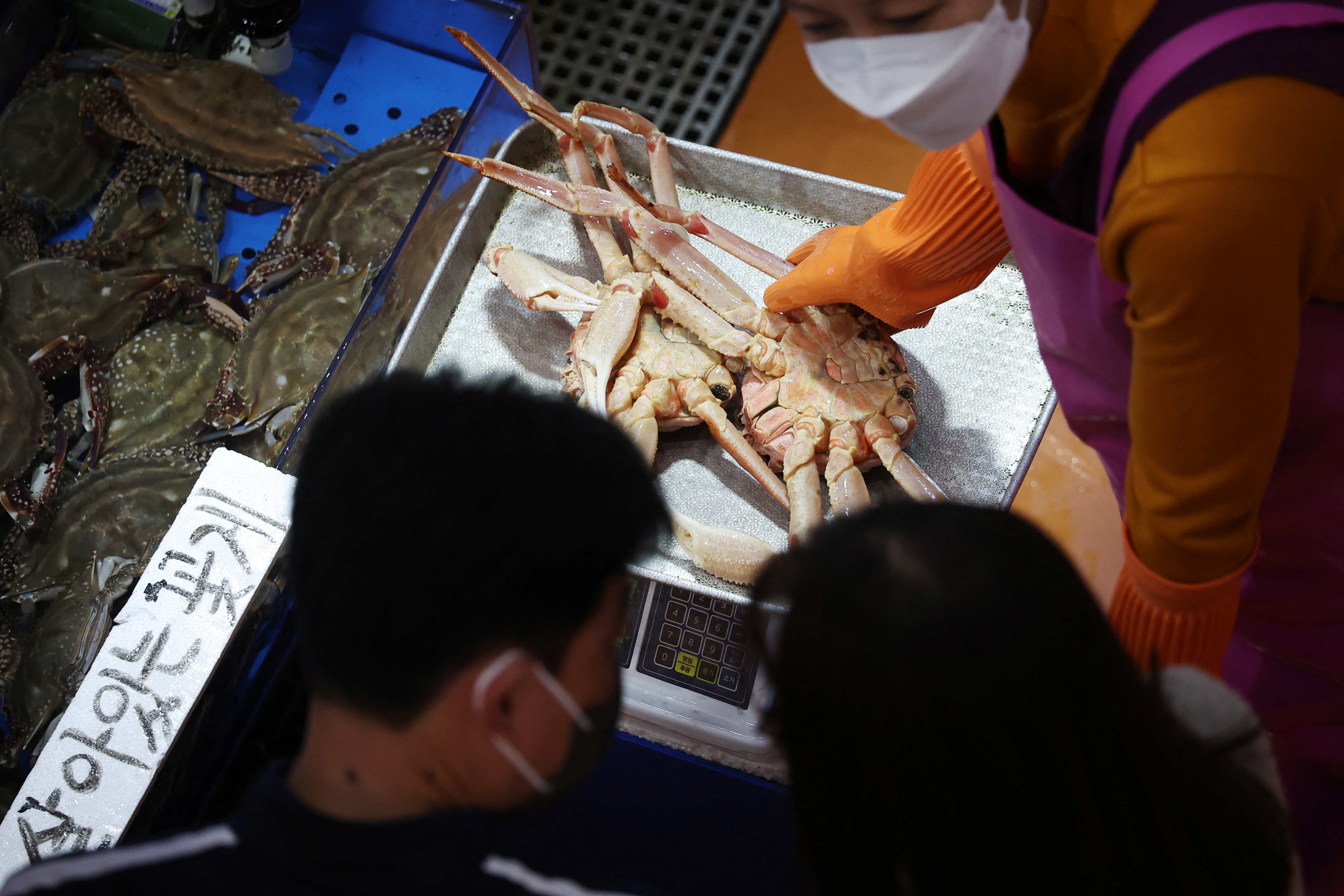 Un comerciante muestra un cangrejo real importado de Rusia a un cliente en el mercado mayorista de pesca de Noryangjin, en Seúl.