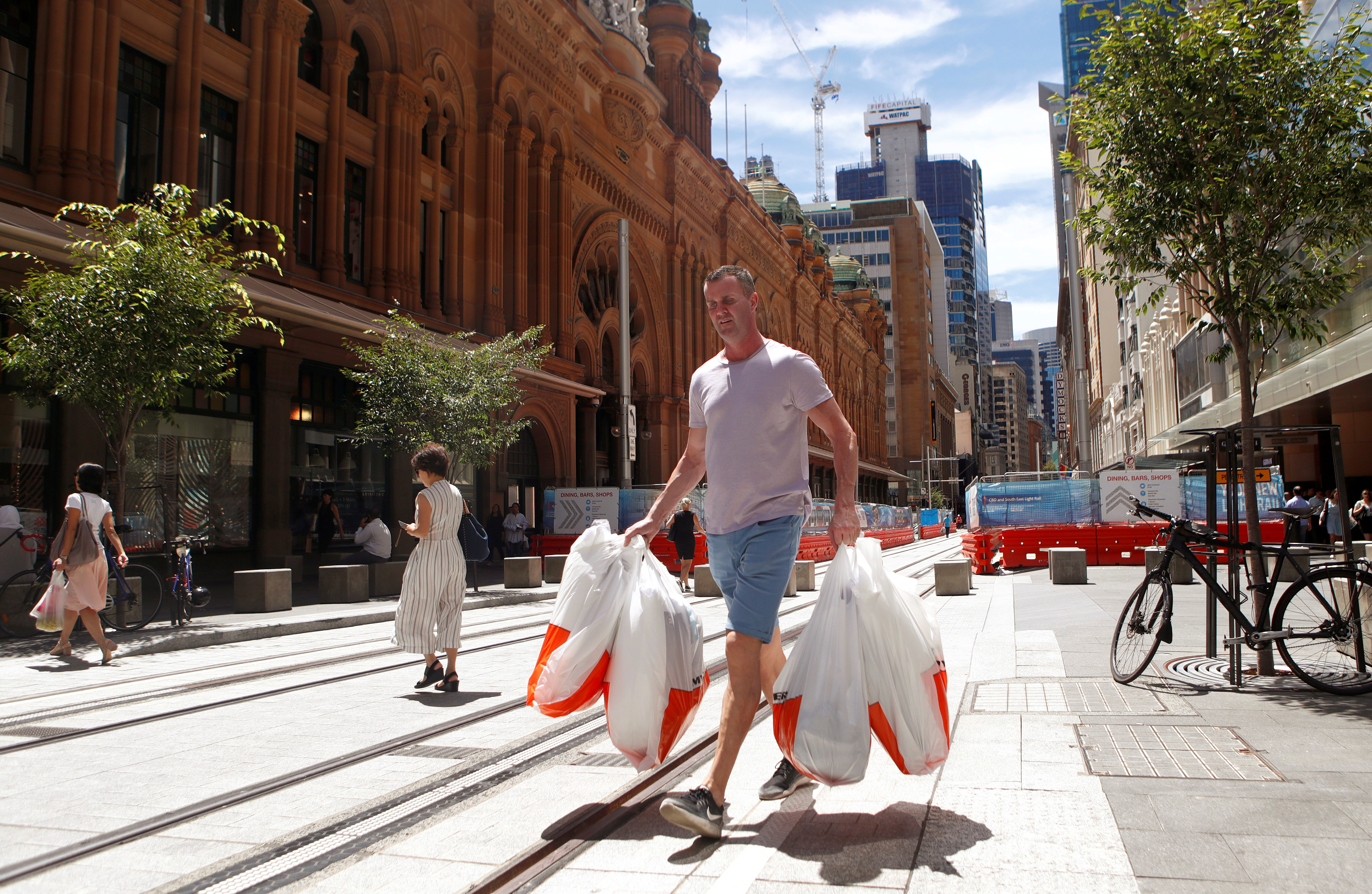 A man carries several shopping bags as he walks along George Street in Sydney