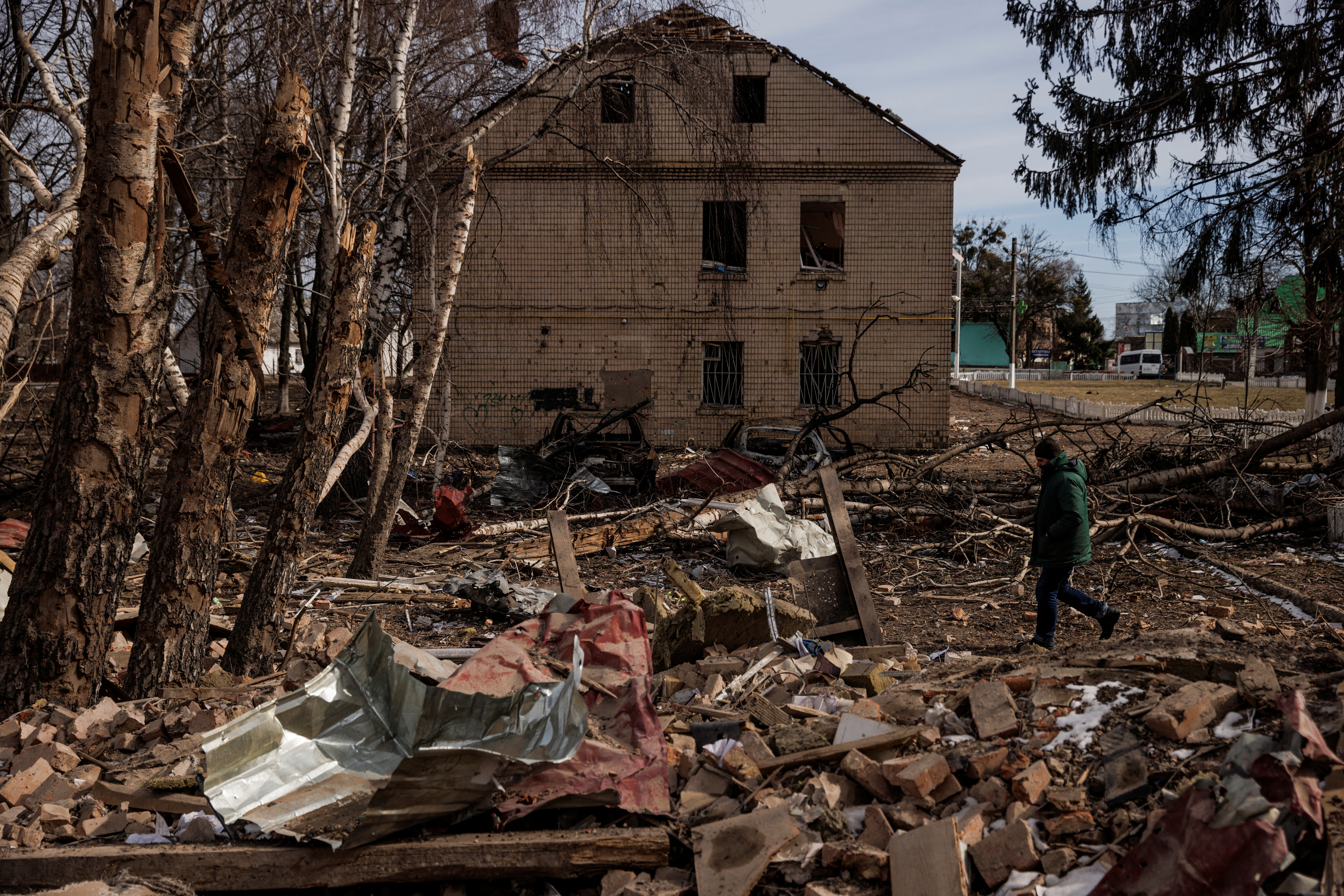 A man walks through the debris of a cultural center and an administration building that were destroyed during aerial bombing, in the village of Byshiv outside Kyiv