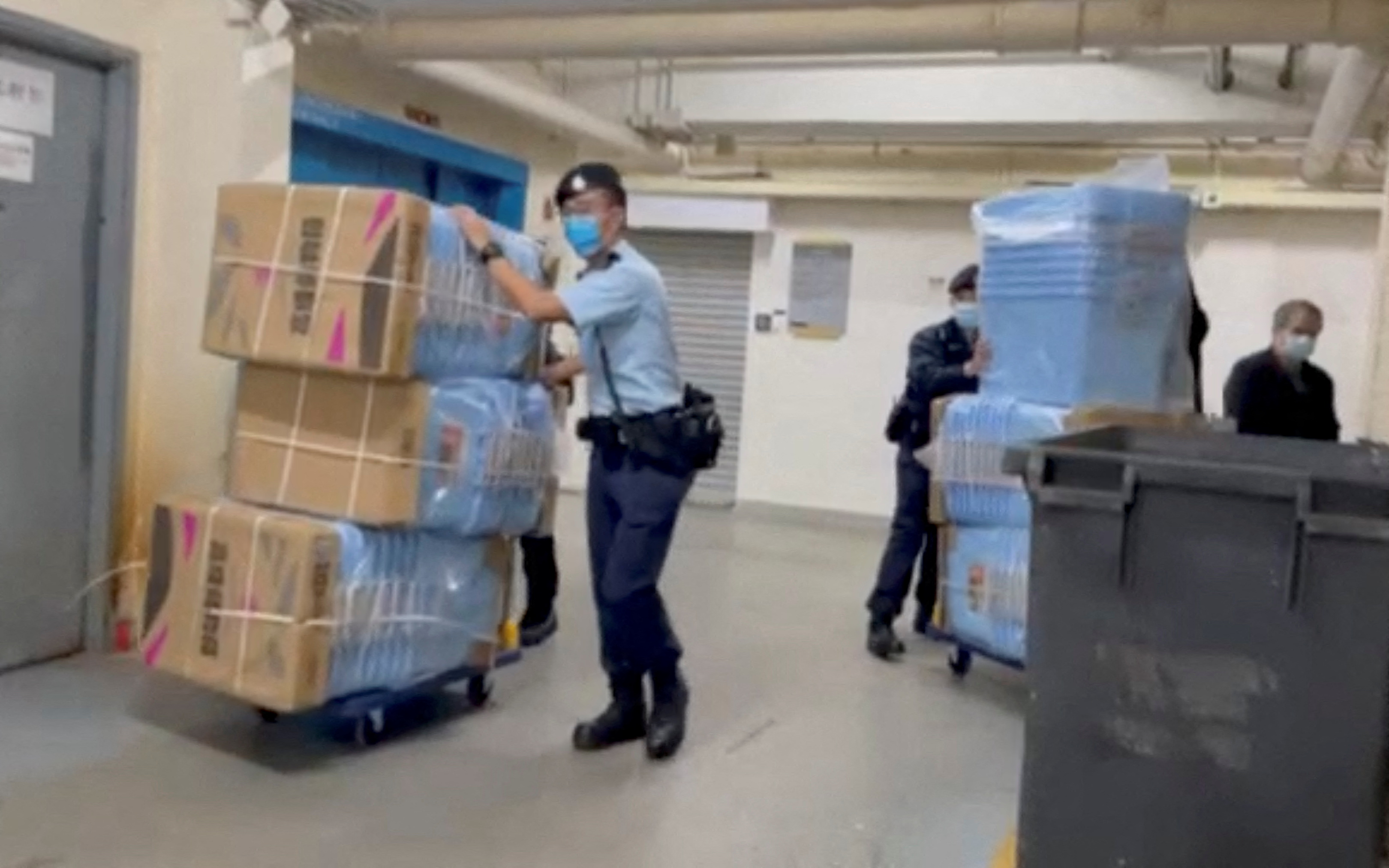 Police officers push boxes to collect evidence during their raid operation at Stand News office in Hong Kong, China
