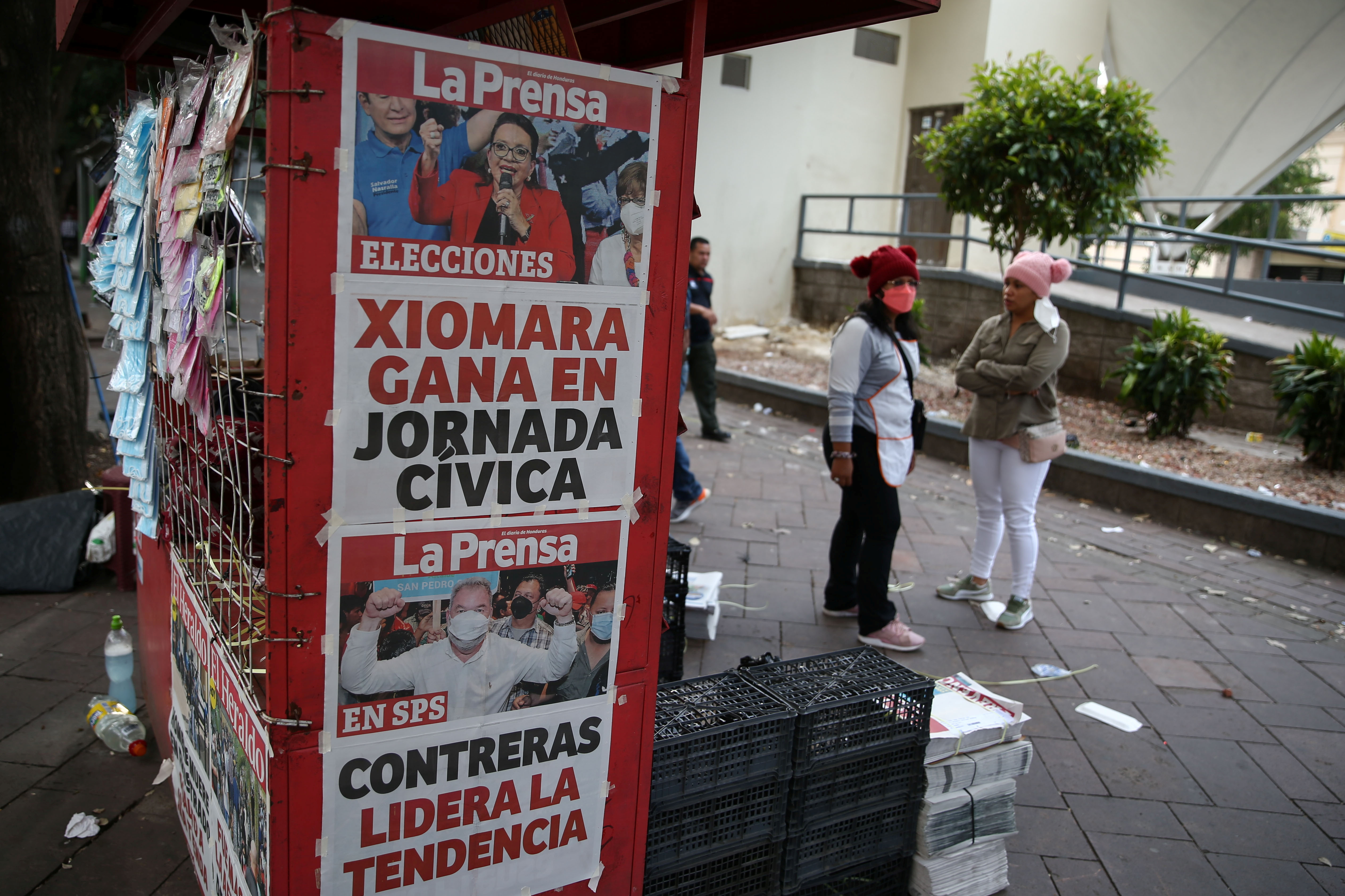 People stand by a newspaper stand that displays cover stories on the preliminary results of the general election in Tegucigalpa, Honduras, November 29, 2021. REUTERS/Jose Cabezas