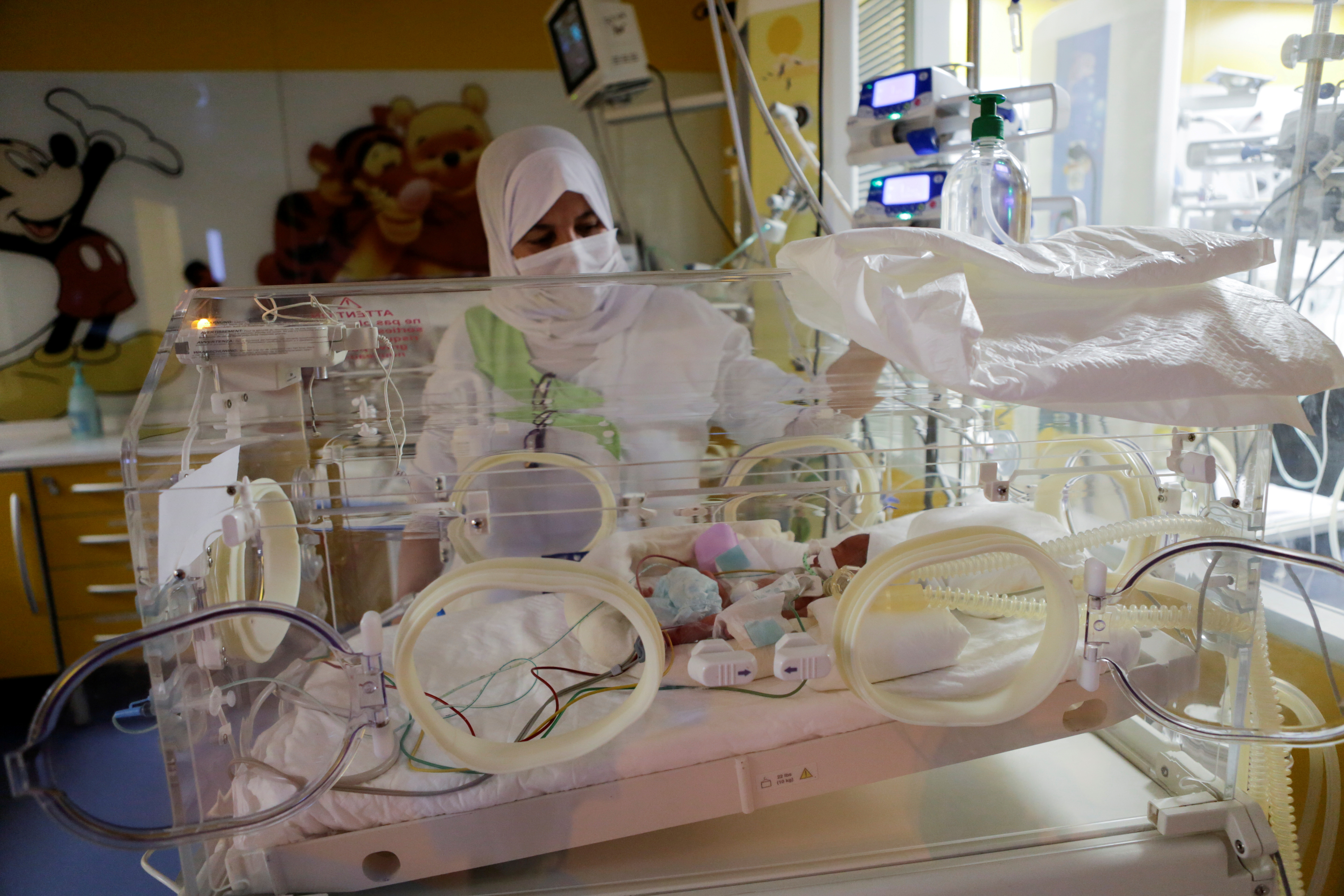 A nurse takes care of one of the newborn nonuplets, lying in an incubator, at the private clinic of Ain Borja in Casablanca