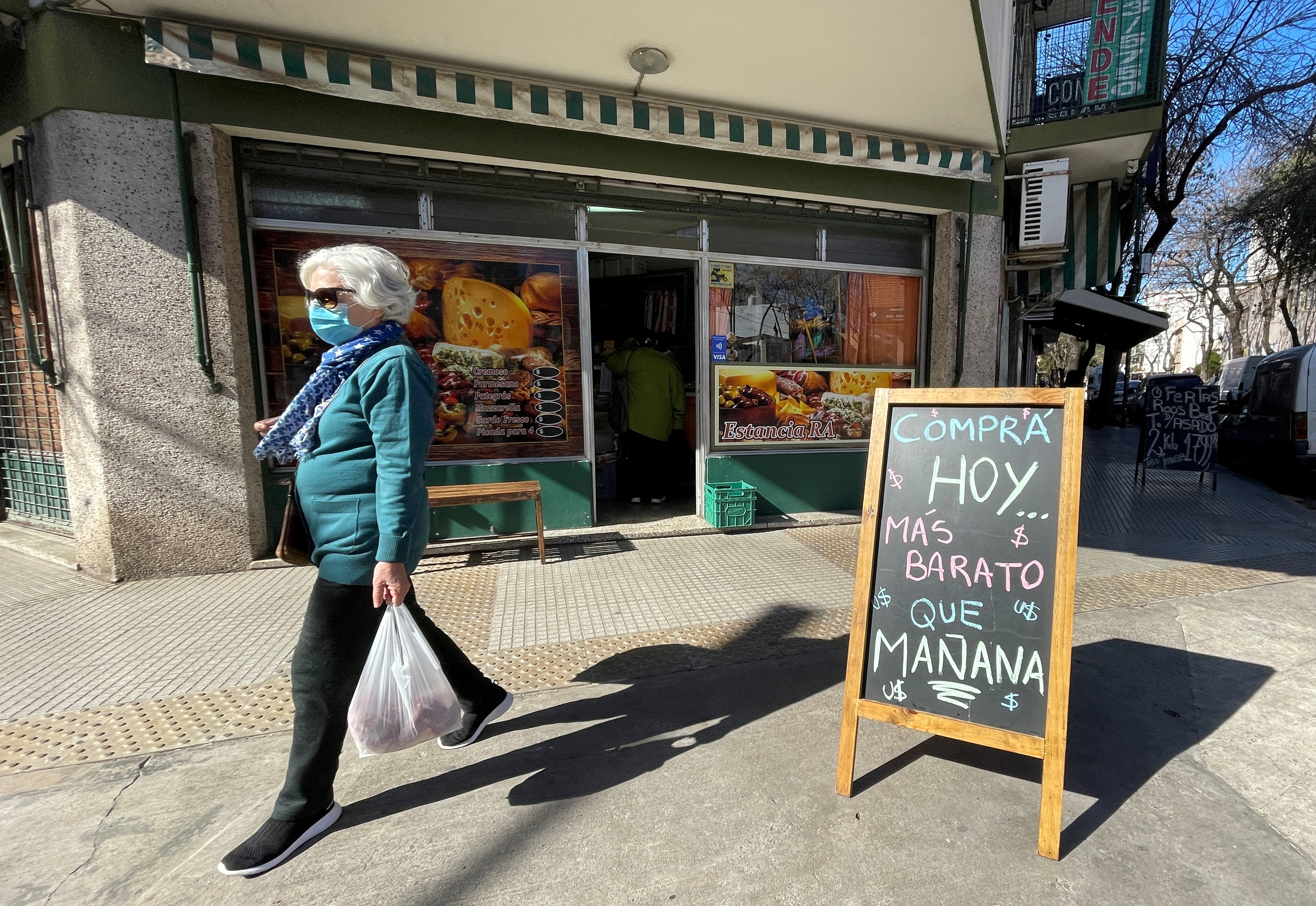 A shopper walks past a placard that reads "Buy today, cheaper than tomorrow", following Argentina's high inflation, as the economic crisis grips, in Buenos Aires