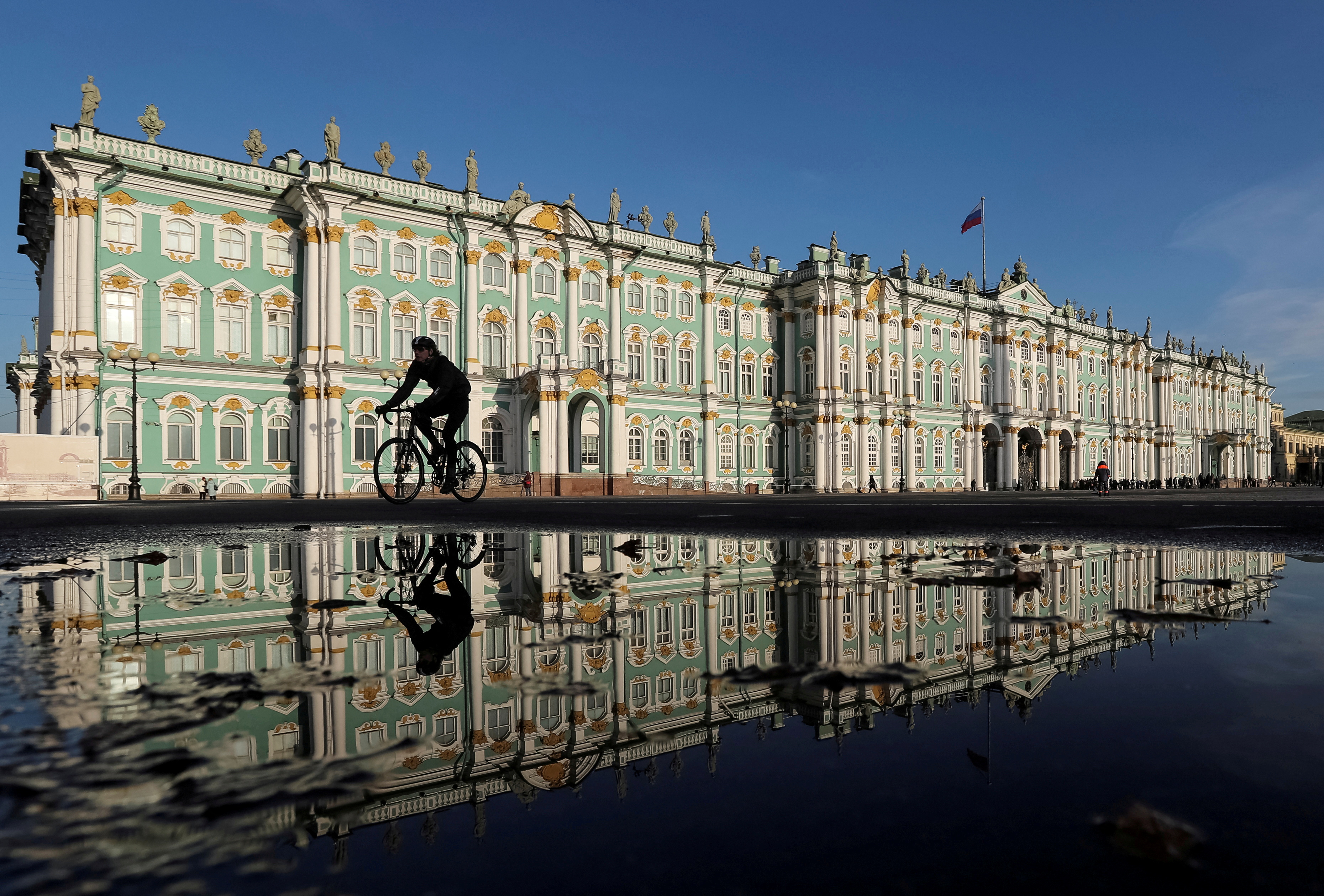 A cyclist rides past the State Hermitage Museum in Saint Petersburg
