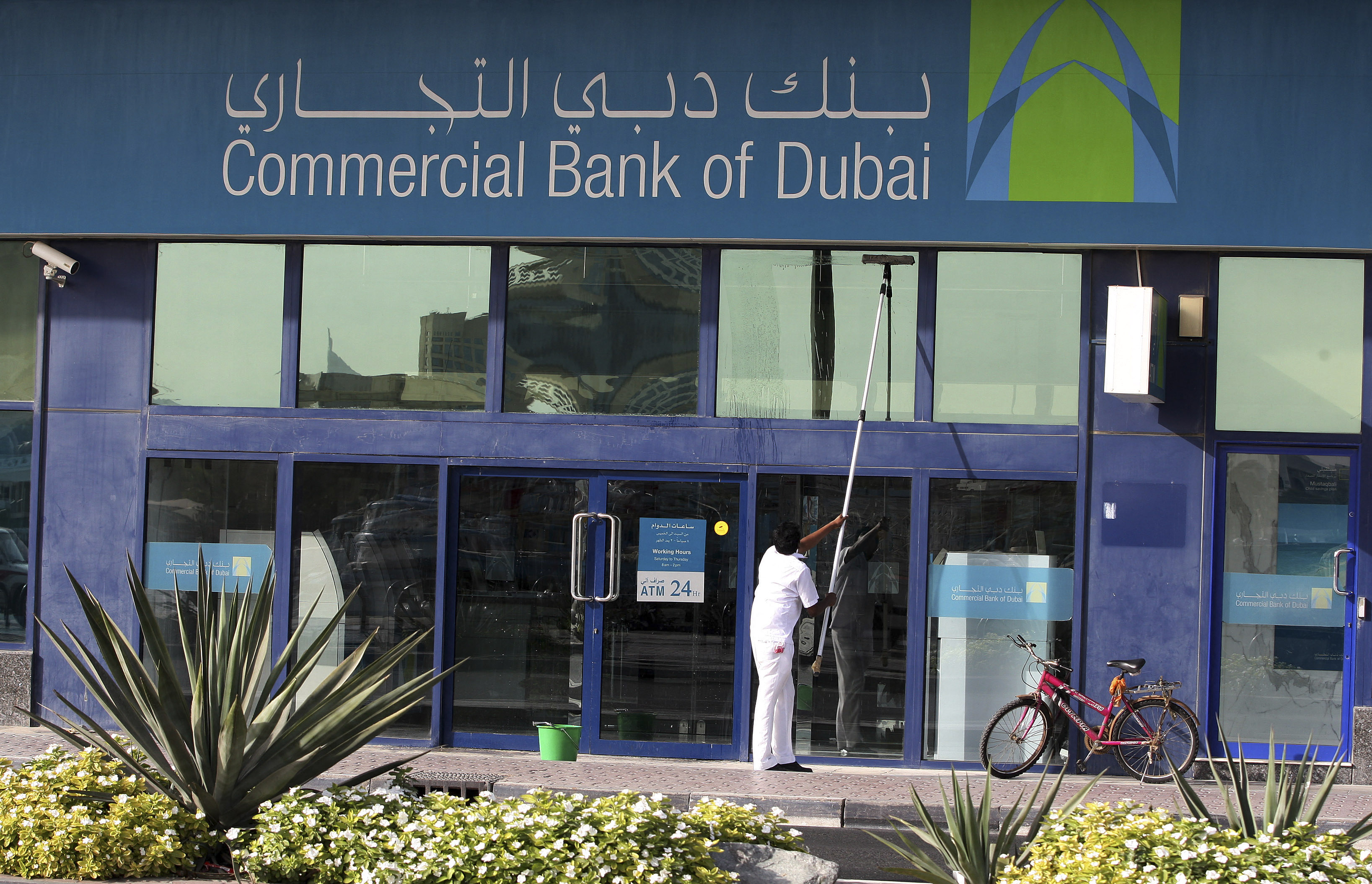A man cleans the windows of a branch of Commercial Bank of Dubai on Baniyas Road in Dubai