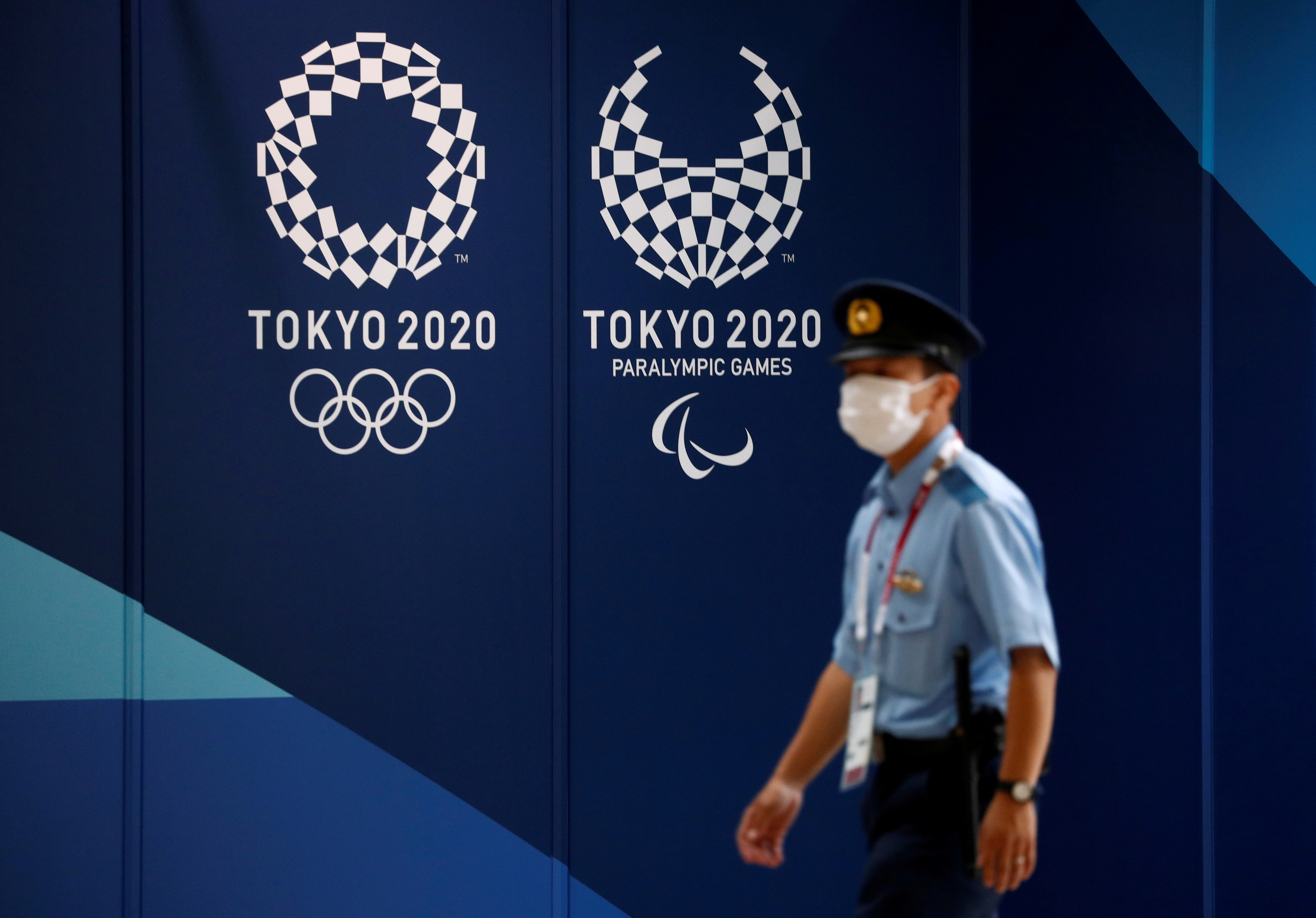 A policeman walks past Tokyo 2020 Olympic signage at the Main Press Center in Tokyo