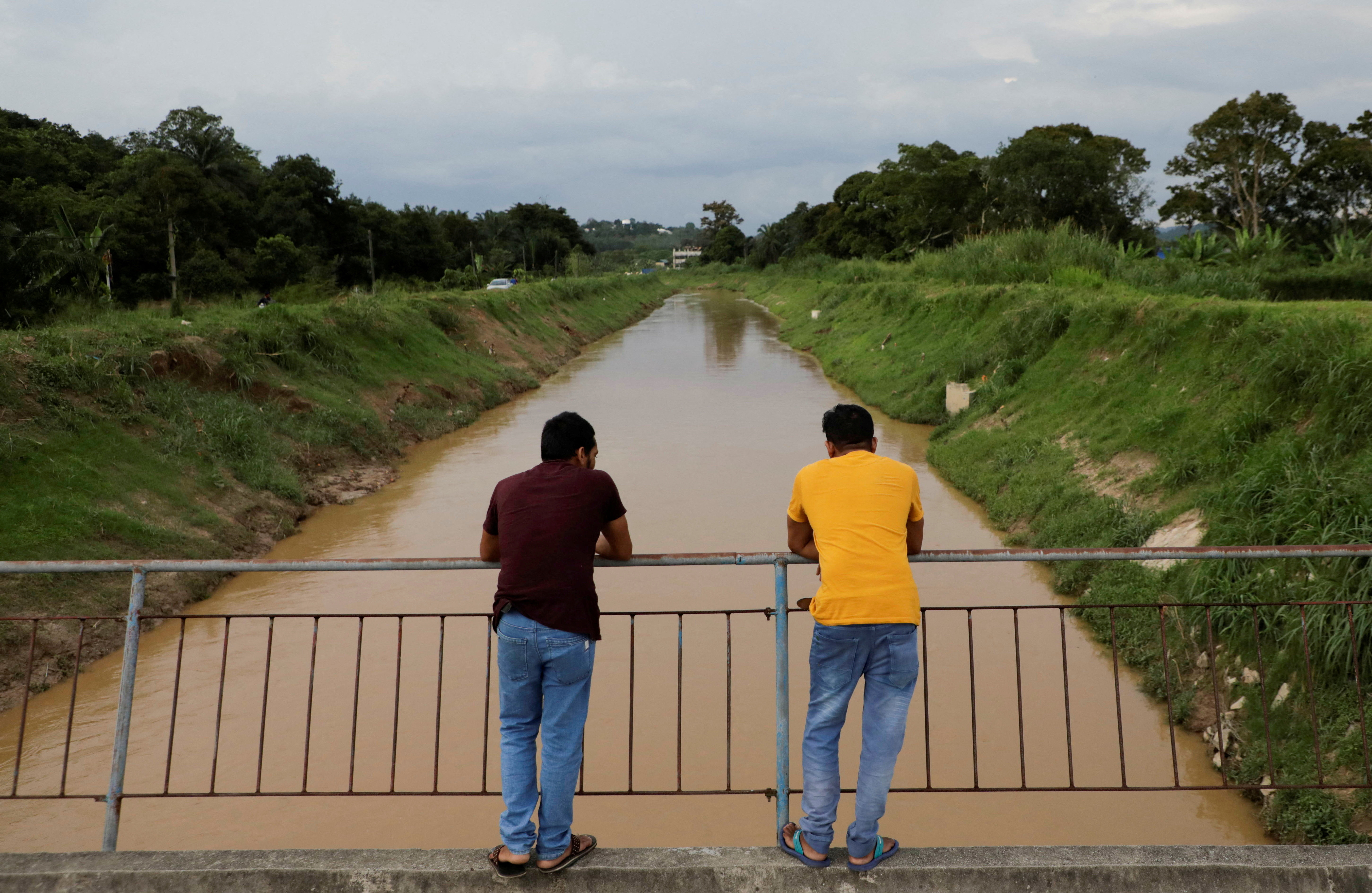 South Asian migrant workers stand on a bridge in Sepang