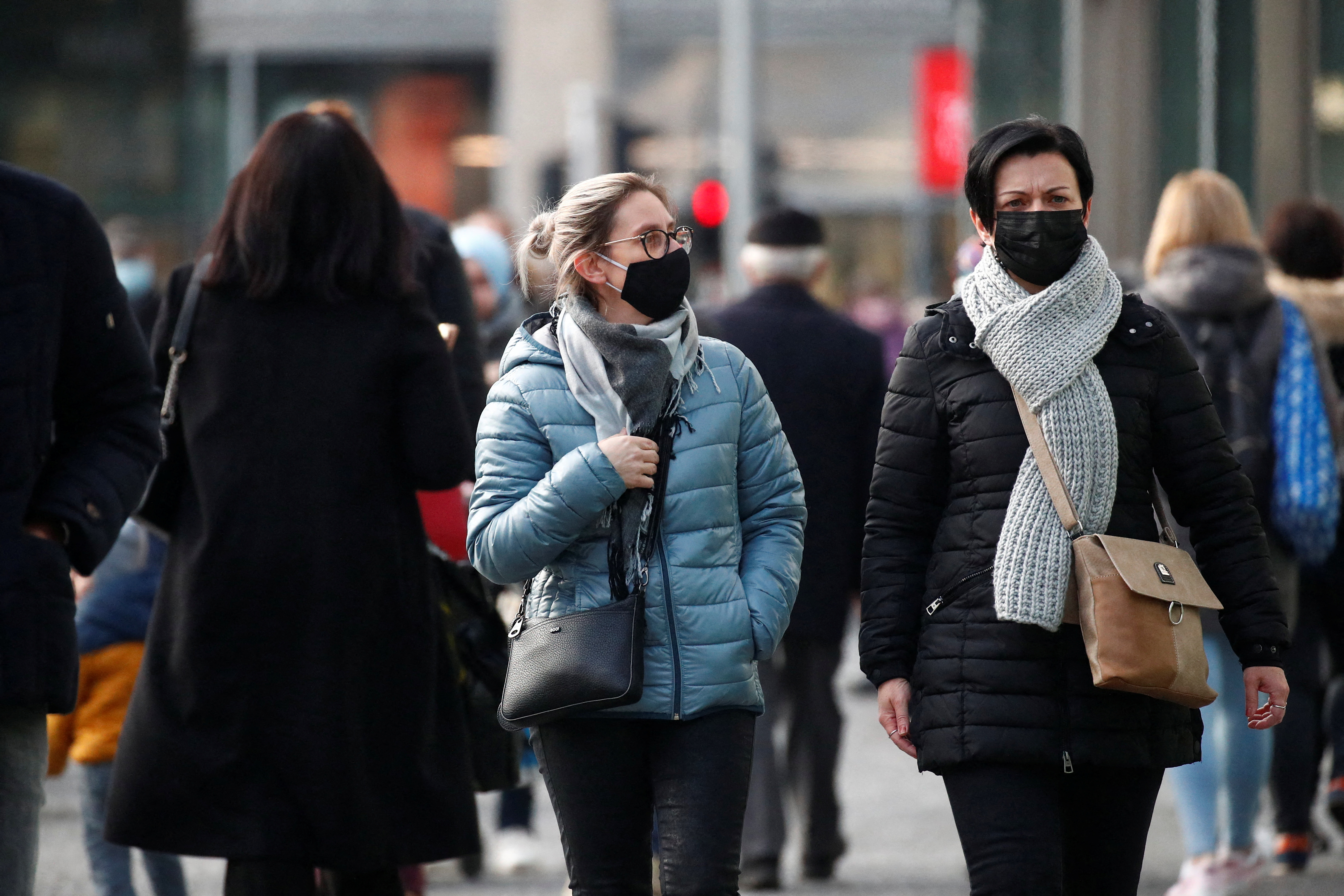 People wearing protective face masks walk on a street in Brussels