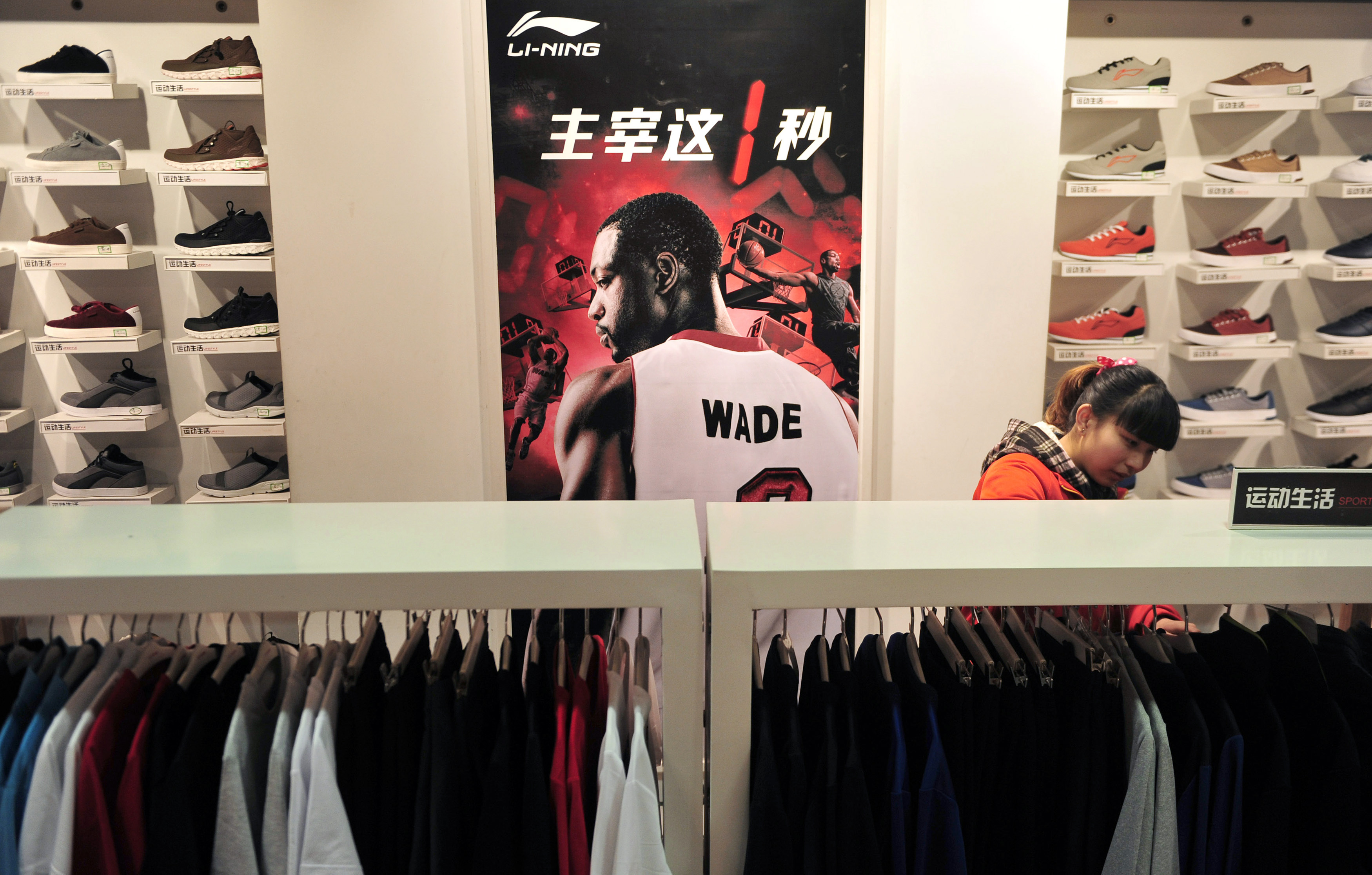 Customer shops at a Li Ning sportswear store in front of a poster of NBA basketball player Dwyane Wade in Shenyang