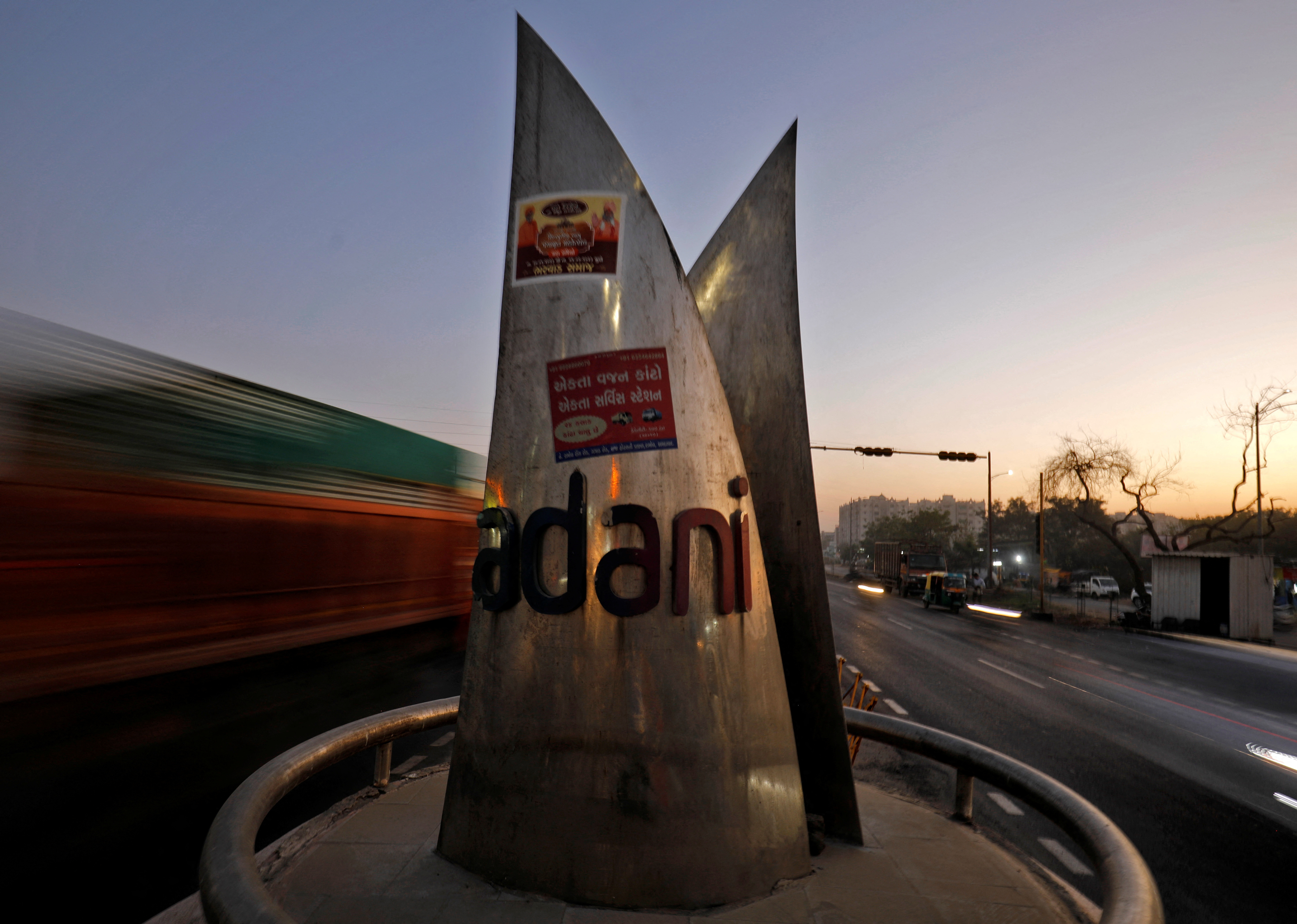 Traffic moves past the logo of the Adani Group installed at a roundabout on the ring road in Ahmedabad