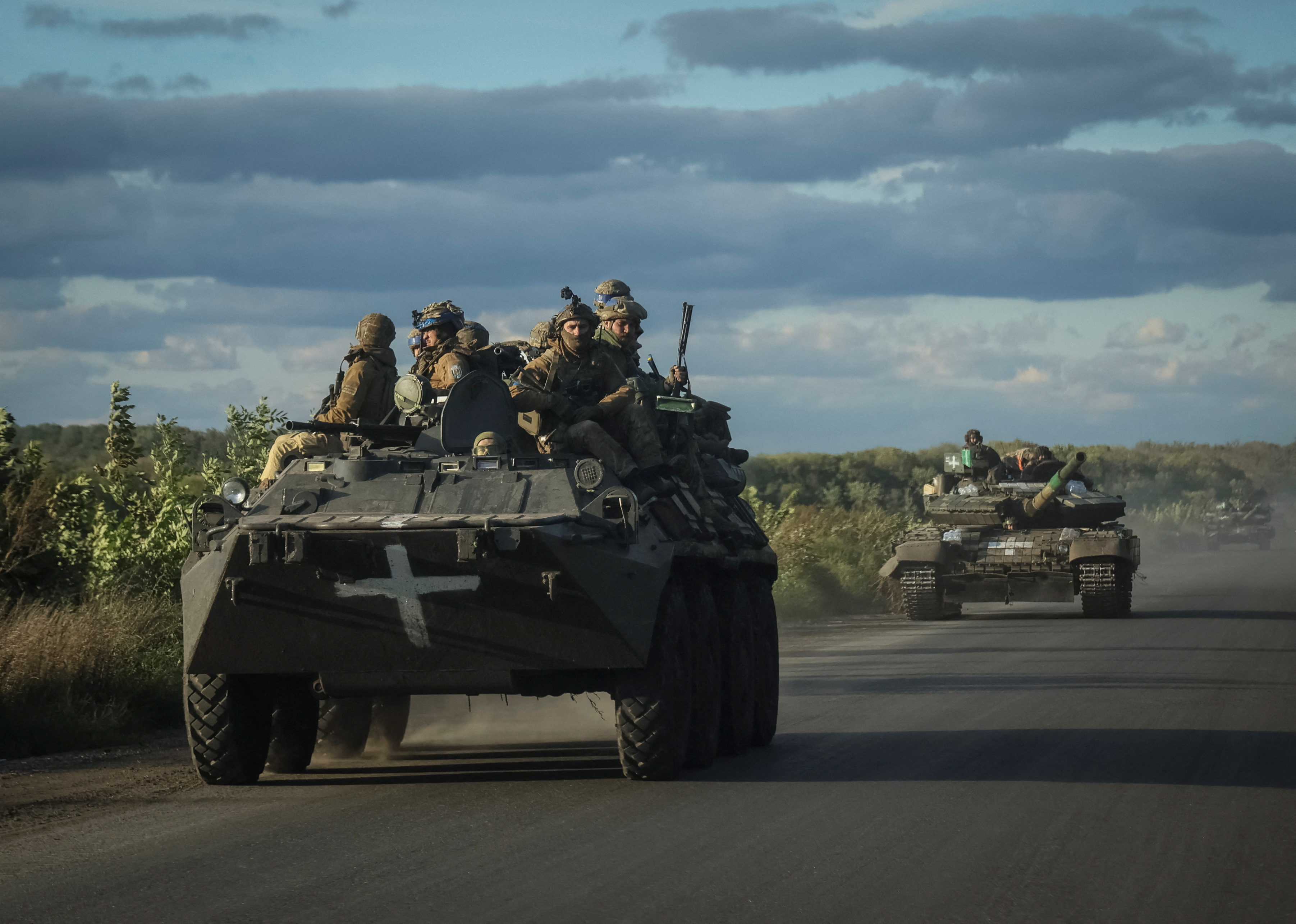 Ukrainian servicemen ride on Armoured Personnel Carrier (APC) and a tank in the town of Izium