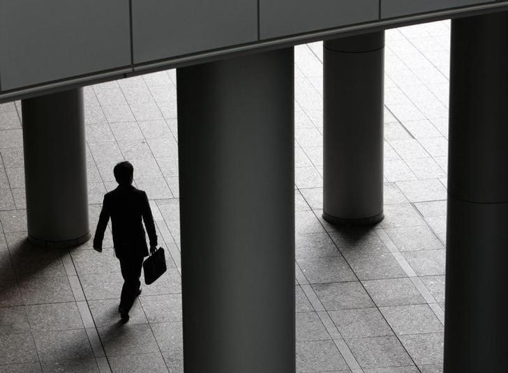 A businessman walks past pillars in Tokyo