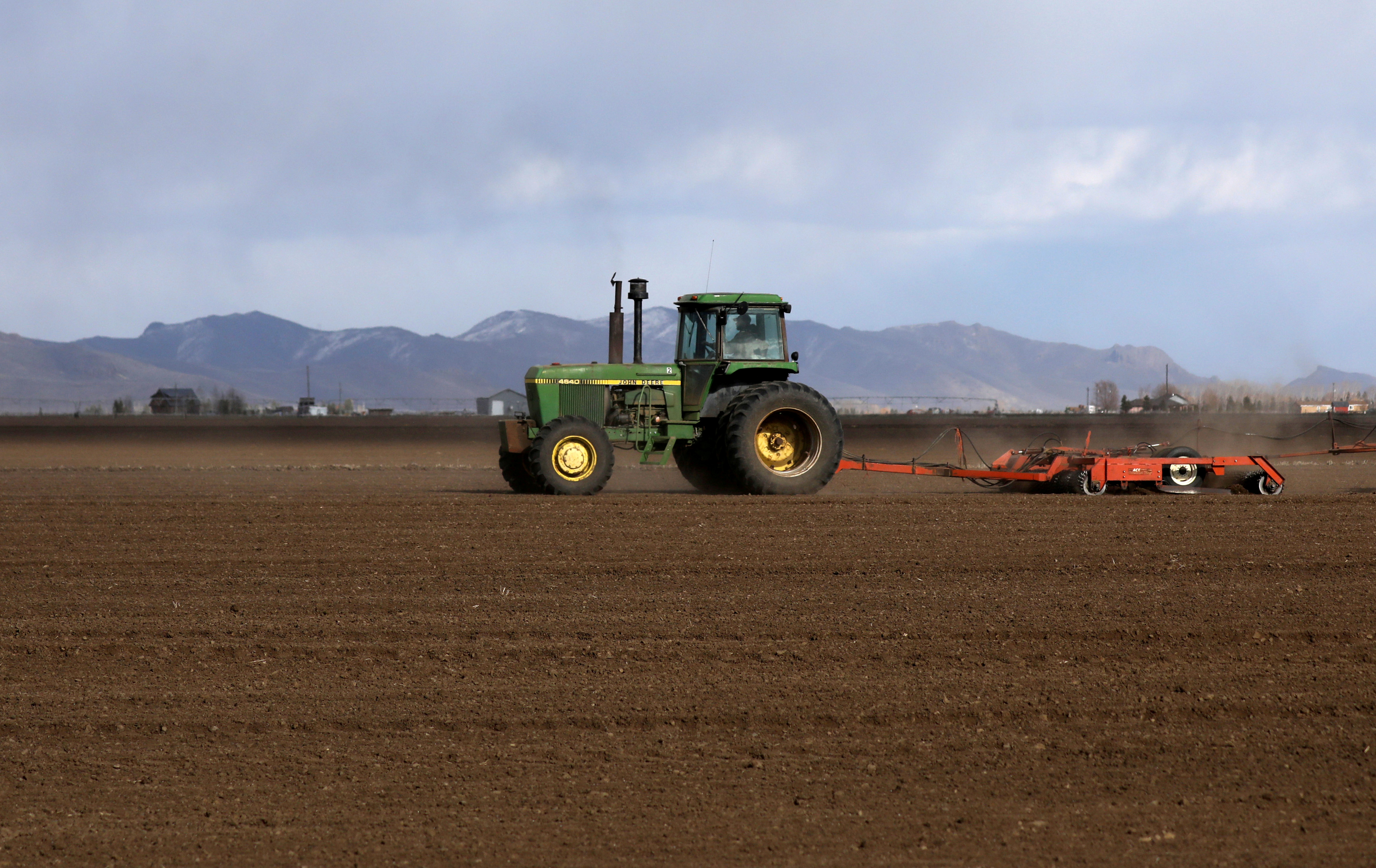 A farmer plows a field with a tractor in rural Idaho