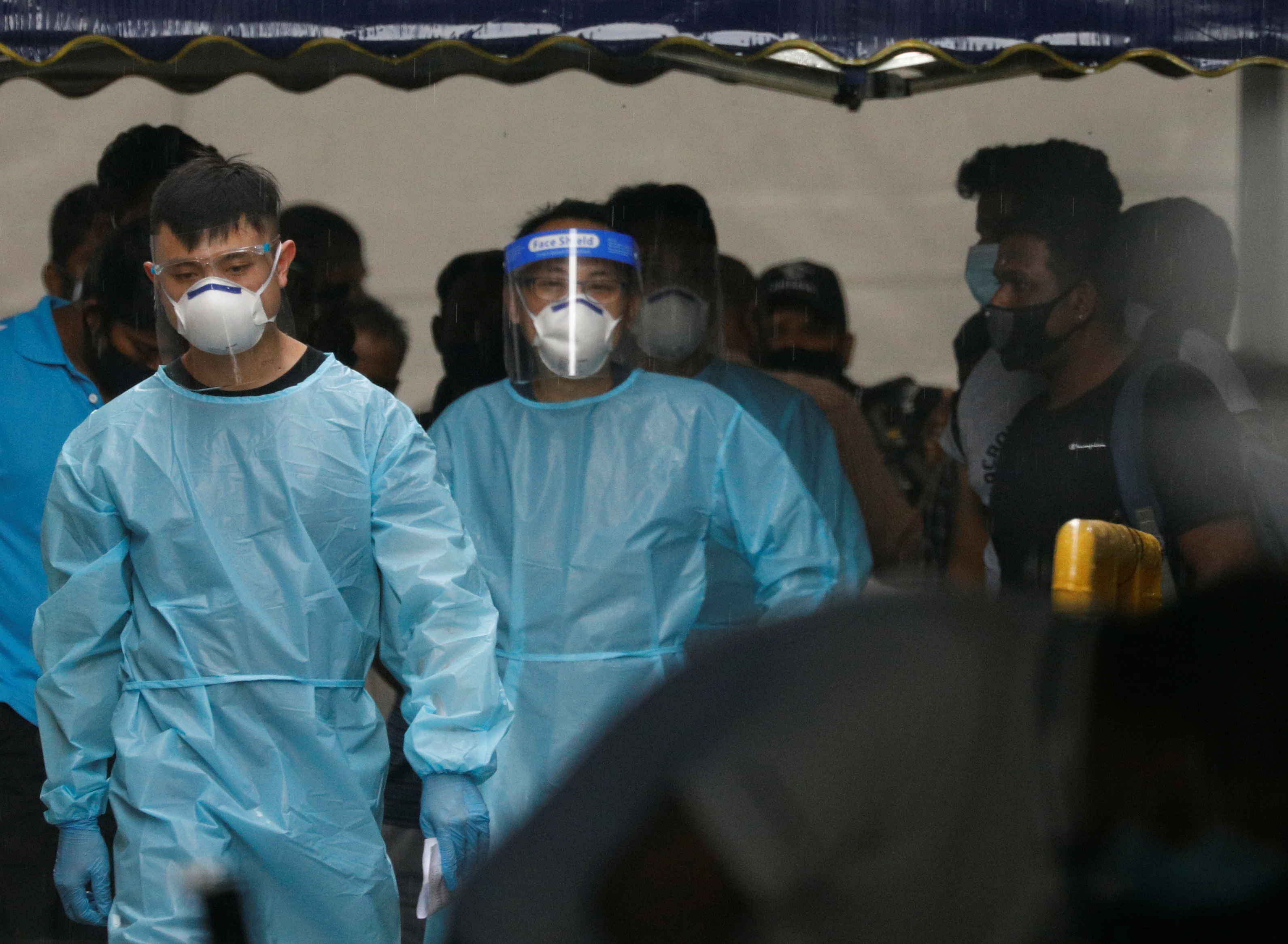 Personnel in protective garment usher a group of migrant workers to take a bus to a government quarantine facility after workers were tested positive for the coronavirus disease (COVID-19) at Westlite Woodlands dormitory in Singapore April 22, 2021.  REUTERS/Edgar Su