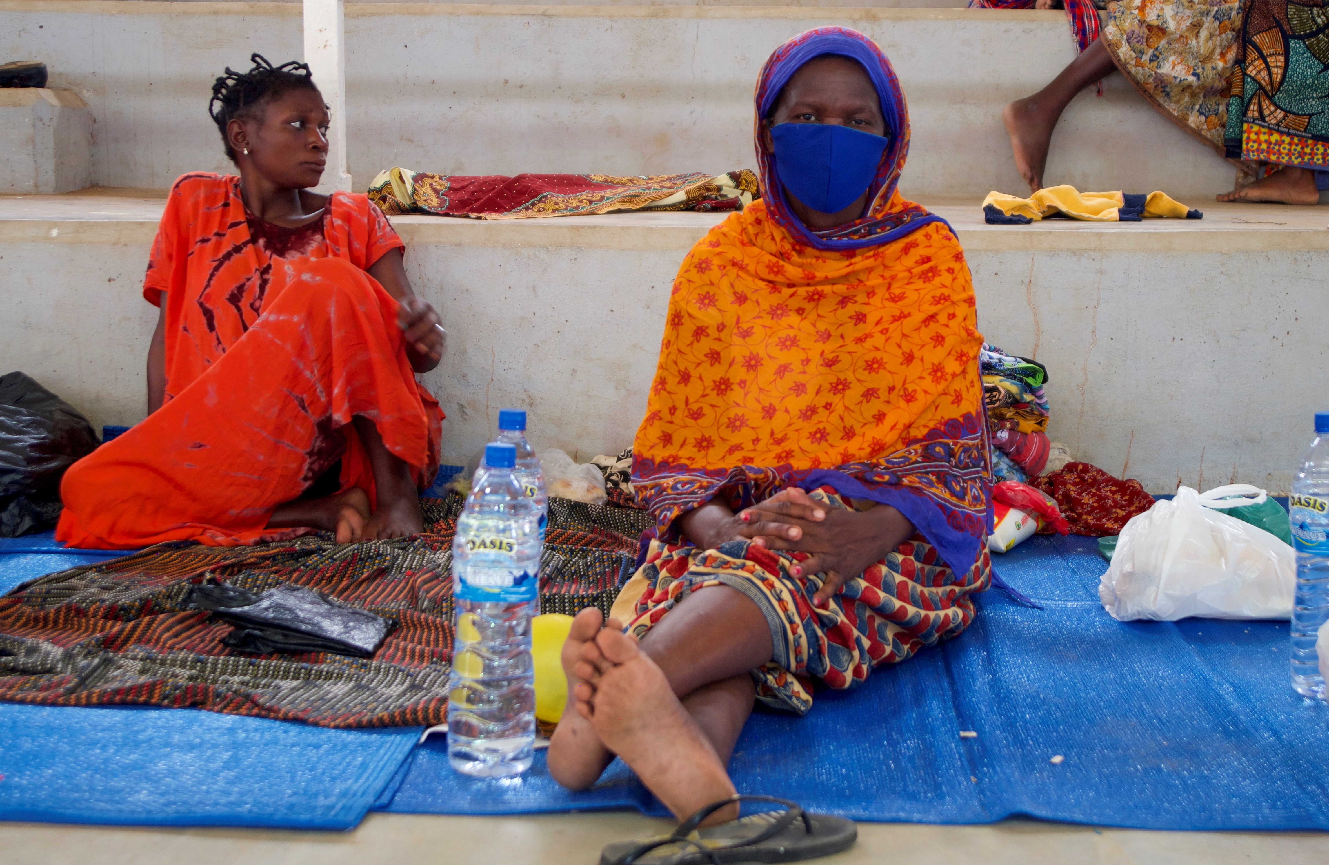 Displaced women sit on mats, at a displacement centre in Pemba