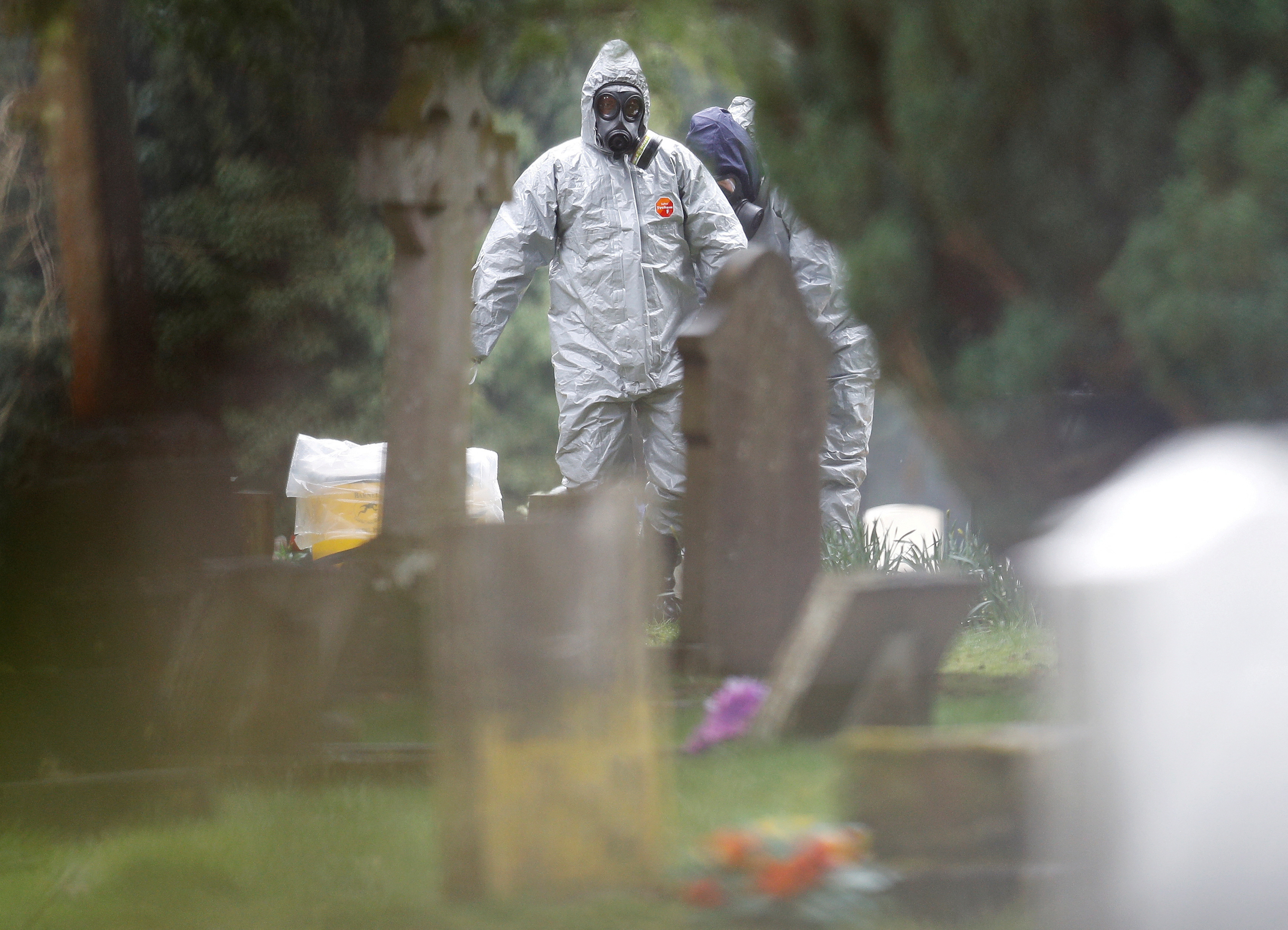 Members of the emergency services help each other to remove their protective suits at the site of the grave of Luidmila Skripal, wife of former Russian inteligence officer Sergei Skripal, at London Road Cemetery in Salisbury