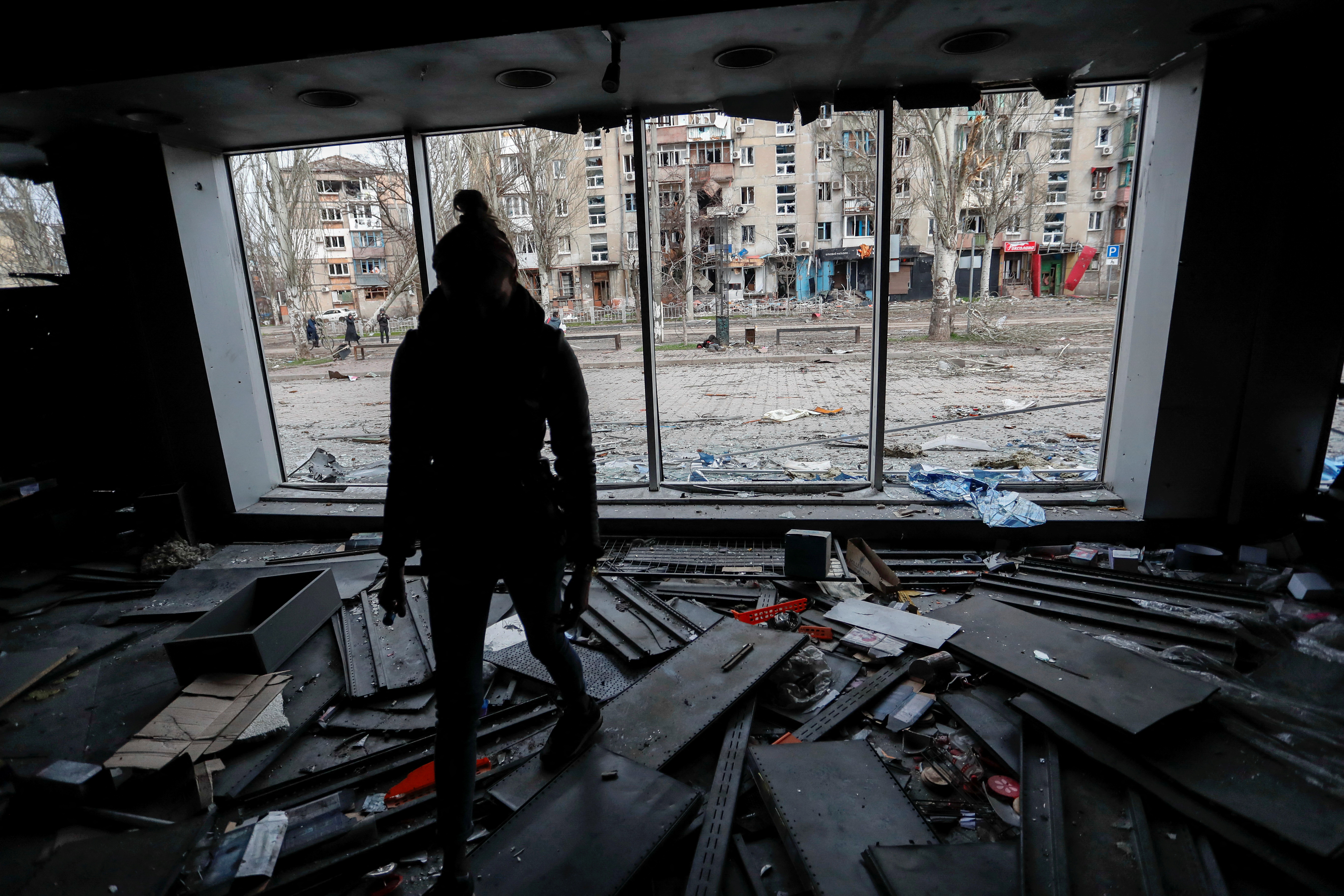 A woman walks inside a damaged building in Mariupol