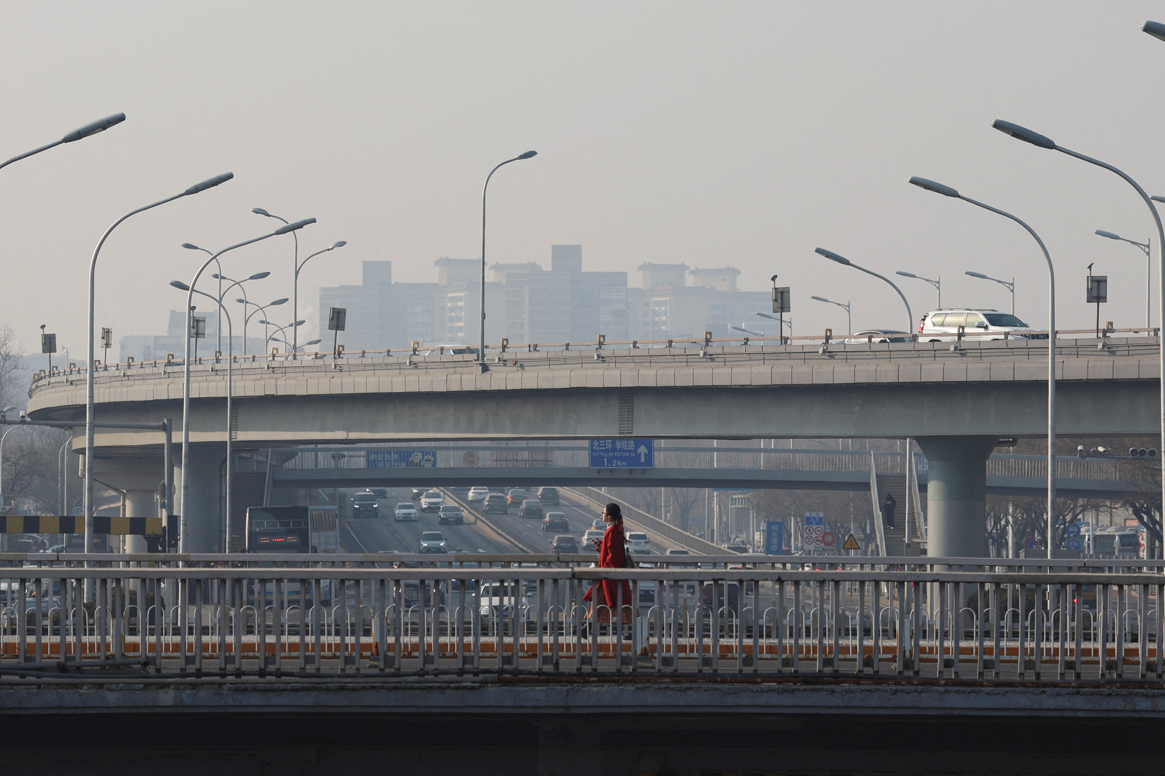 Pedestrian walks past car traffic in Beijing