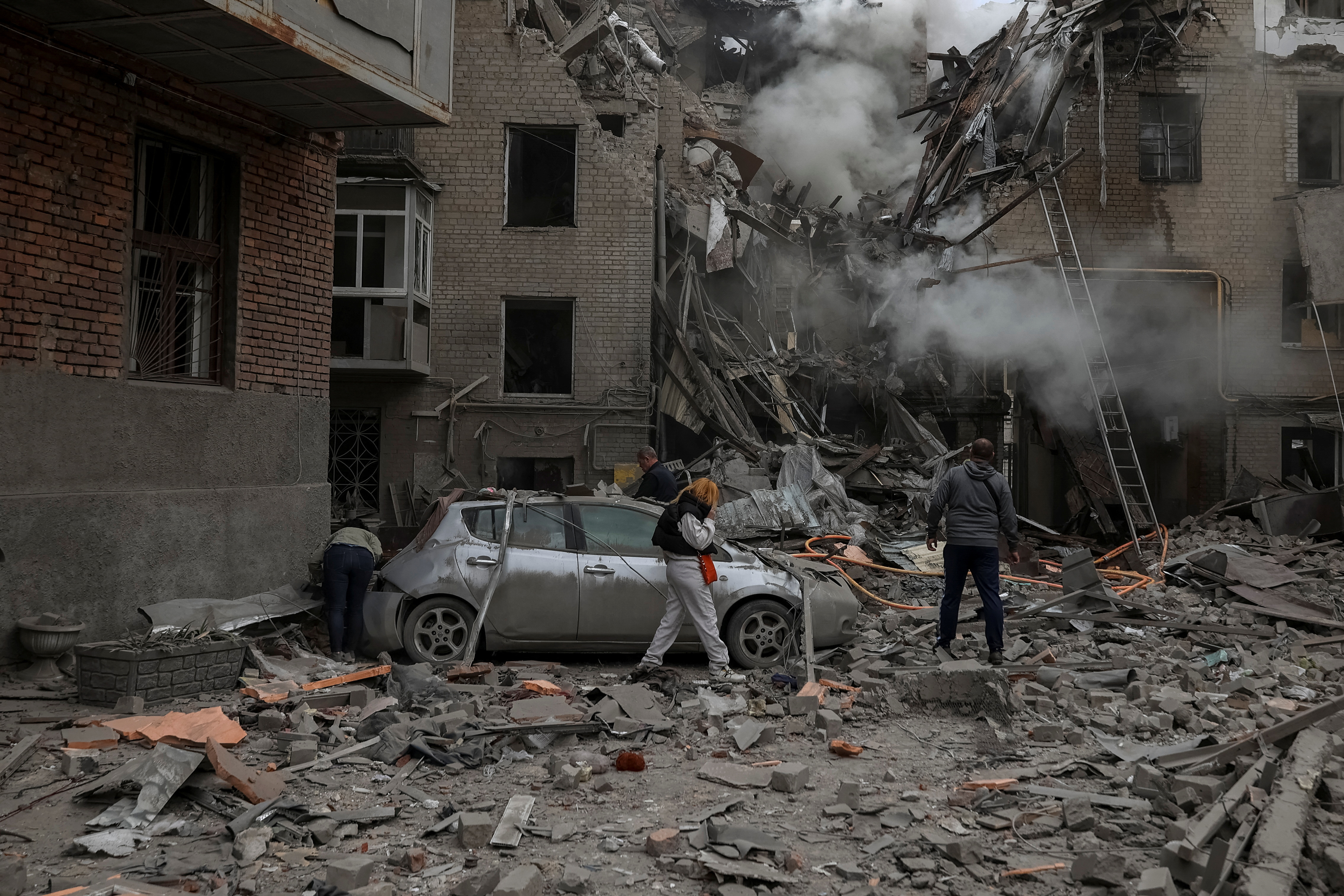 Local residents look at debris of a residential building damaged by a Russian military strike in Kharkiv