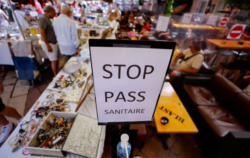 A coronavirus disease (COVID-19) health pass poster is seen in a restaurant as France brings on tougher restrictions where a proof of immunity will now be required to access most public spaces and to travel by inter-city train, in Nice, France, August 9, 2021. REUTERS/Eric Gaillard/File Photo