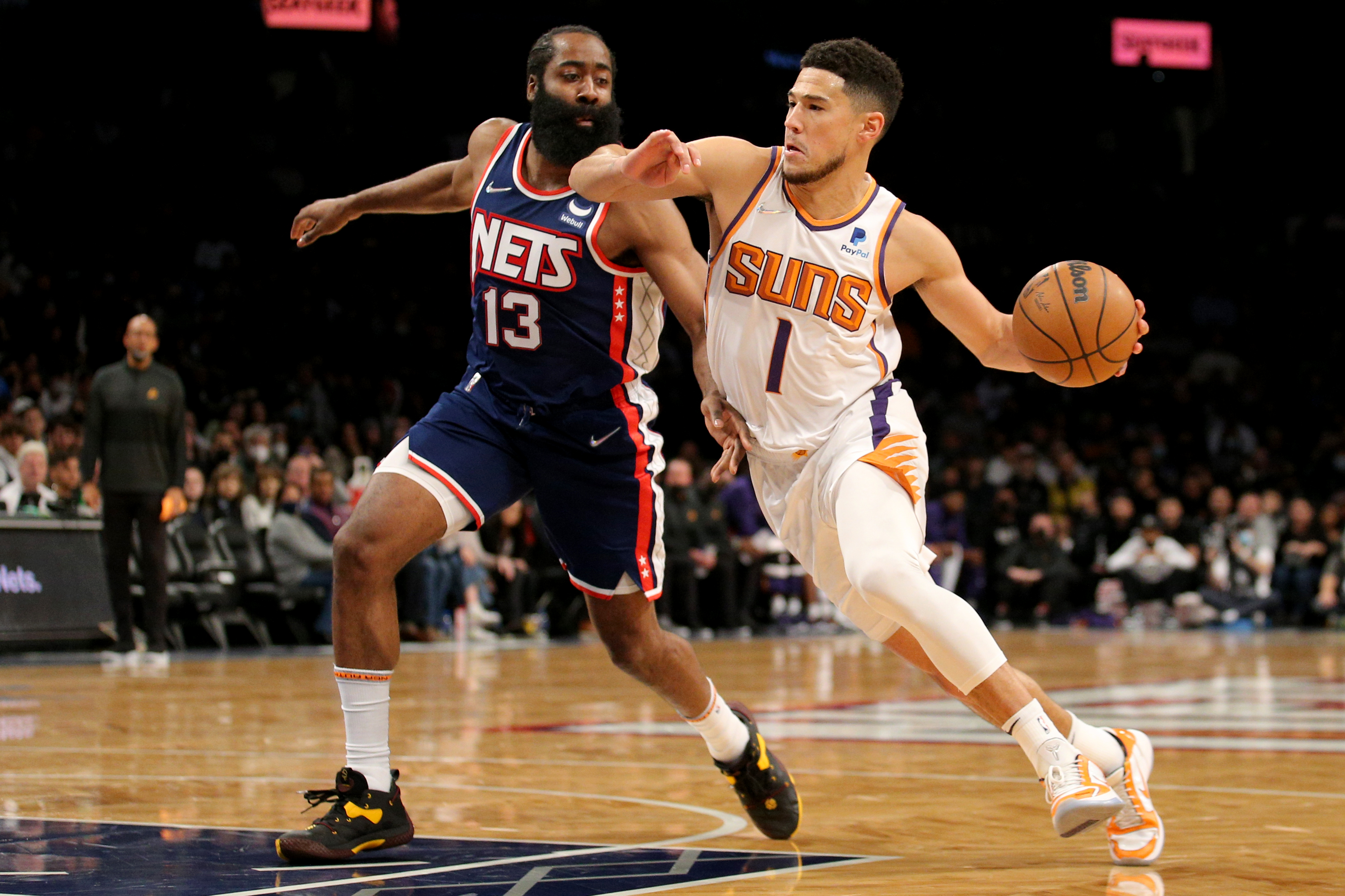 Nov 27, 2021; Brooklyn, New York, USA; Phoenix Suns guard Devin Booker (1) drives to the basket around Brooklyn Nets guard James Harden (13) during the first quarter at Barclays Center. / Brad Penner-USA TODAY Sports