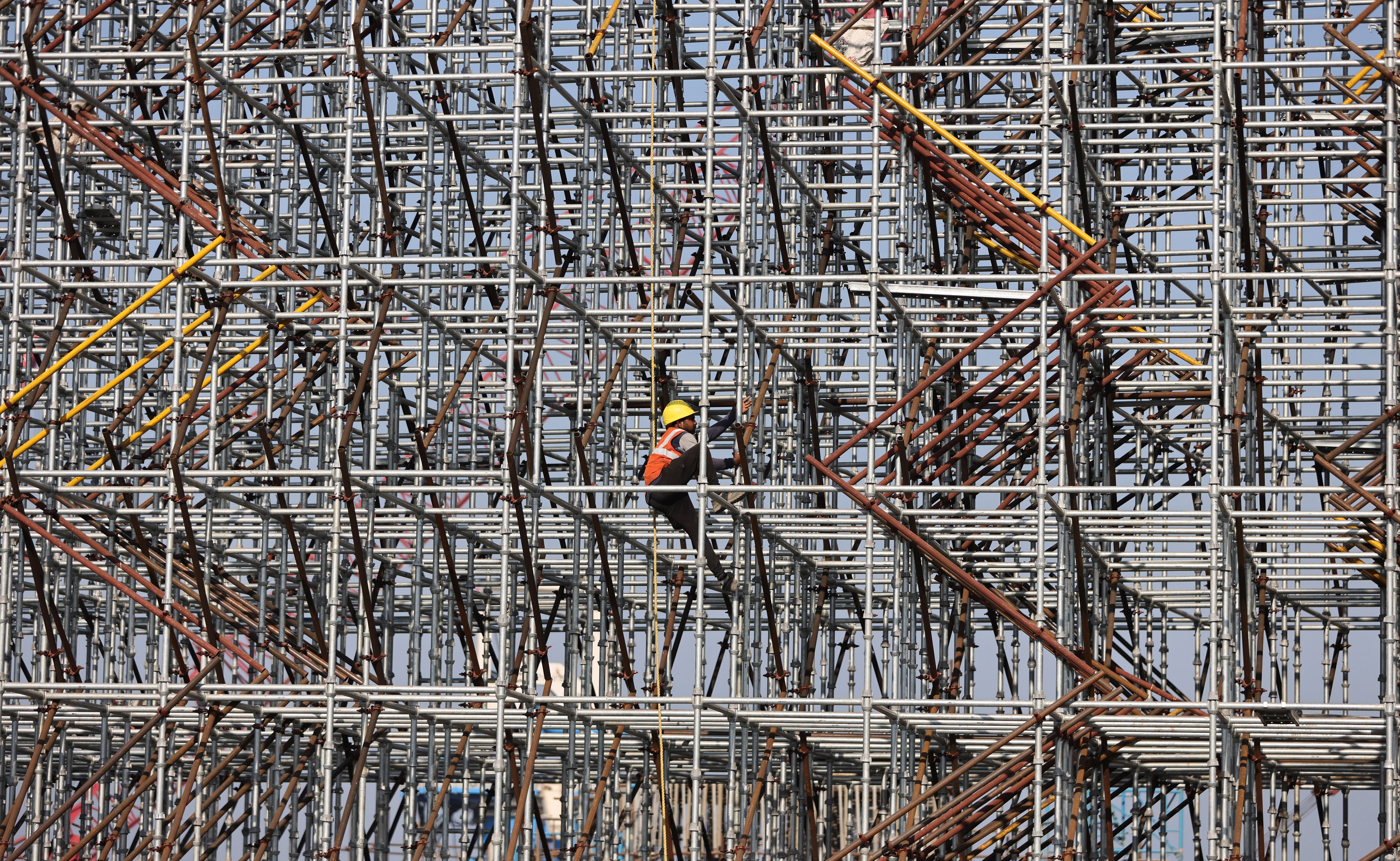 Worker climbs a scaffolding at a construction site in Mumbai