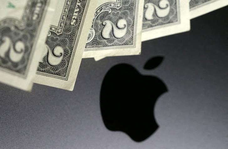 Photo illustration of U.S. dollar banknotes in front of the Apple logo