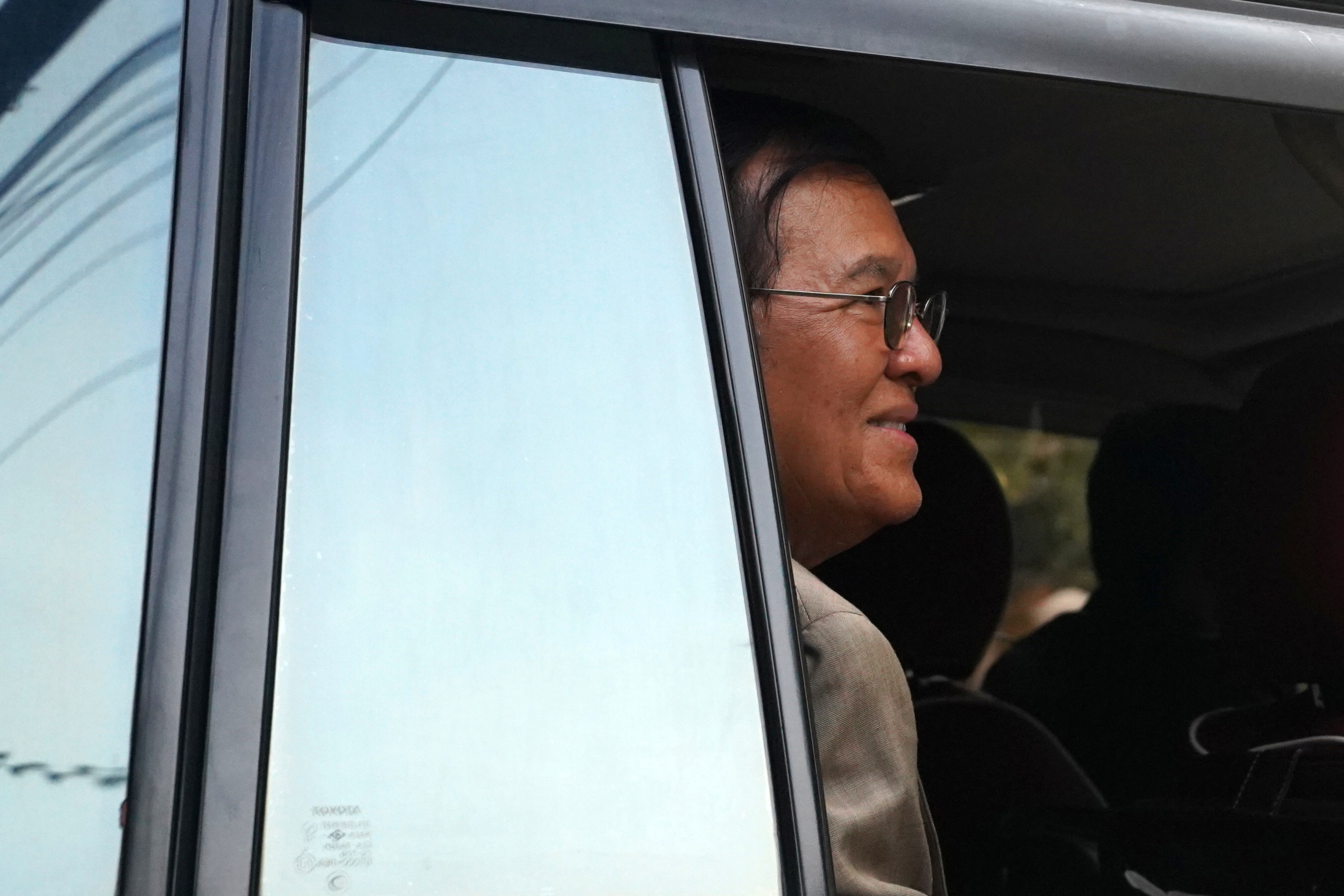 Lãnh đạo phe đối lập Campuchia Kem Sokha vẫy tay từ một chiếc xe khi rời khỏi nhà để tham dự phiên điều trần về phiên tòa xét xử tội phản quốc của ông ở Phnom Penn