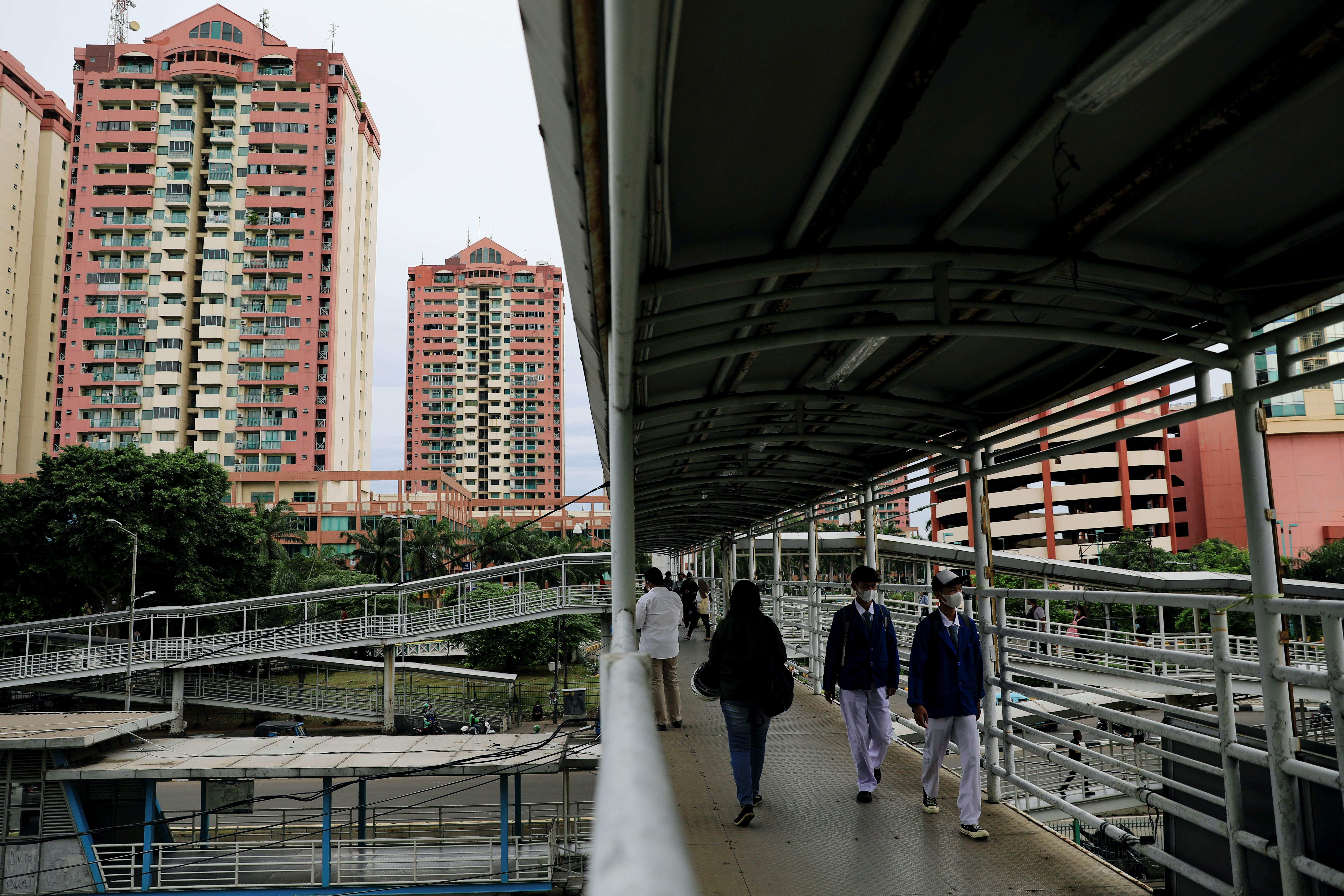 People wearing protective masks walk on a pedestrian bridge amid the spread of the Omicron variant of COVID-19, in Jakarta