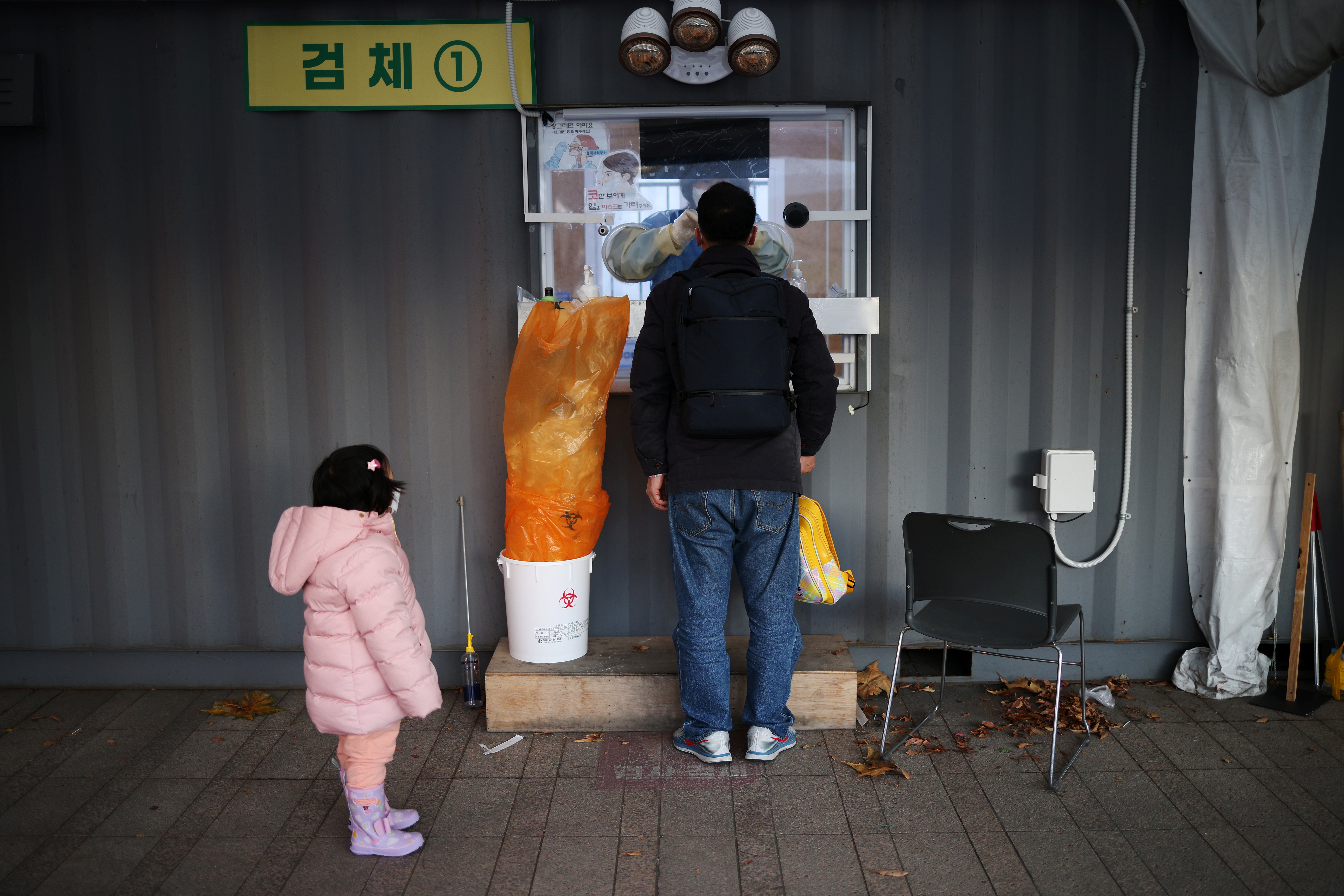 A girl waits for his father undergoing coronavirus disease (COVID-19) test at its testing site in central Seoul