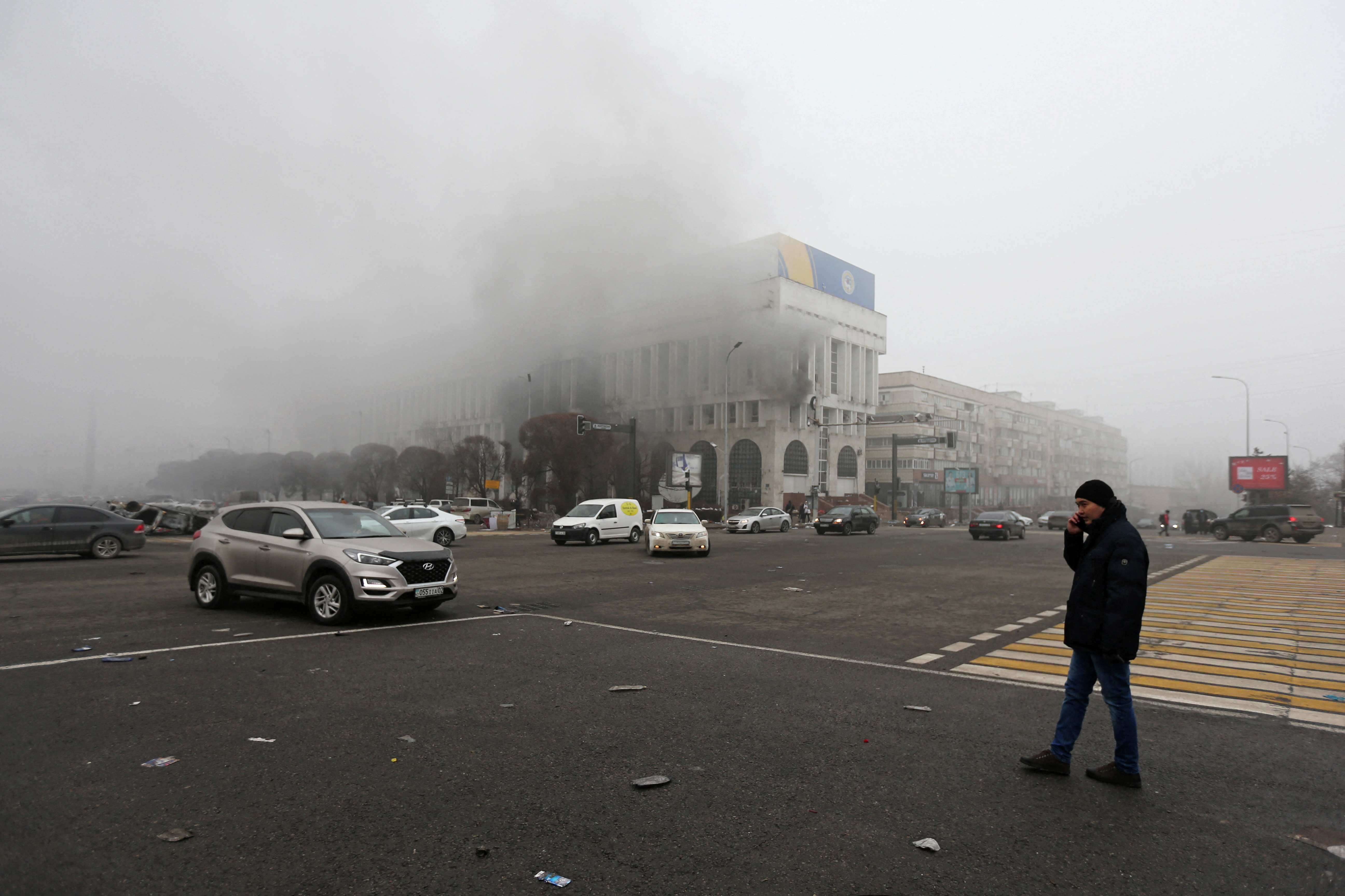 A man stands near the building of the Kazakhstan state TV channel which was torched during protests in Almaty