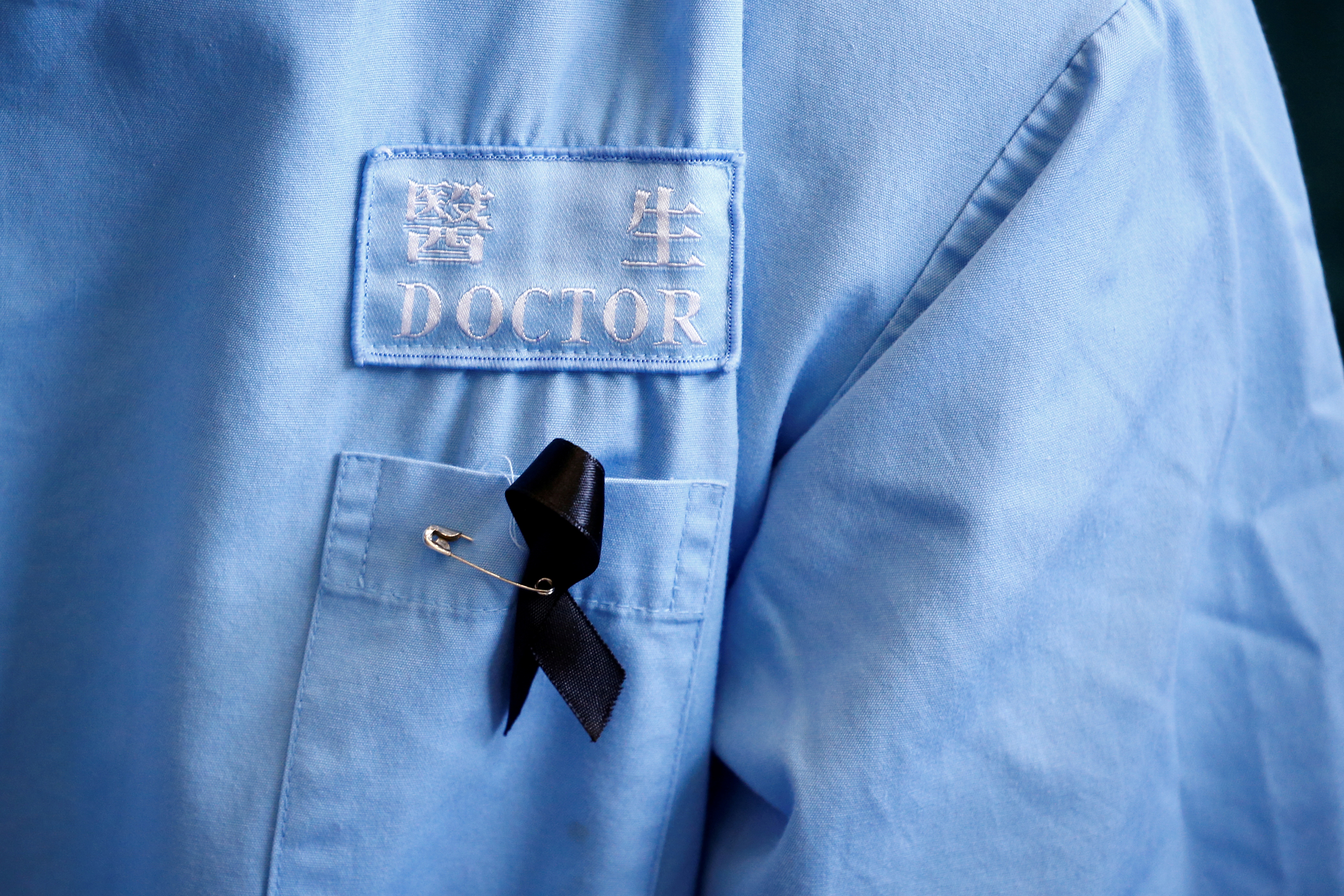 A doctor wears a protest ribbon during a picket of medical staff denouncing police brutality during recent anti-government protests, at Queen Elizabeth Hospital in Hong Kong