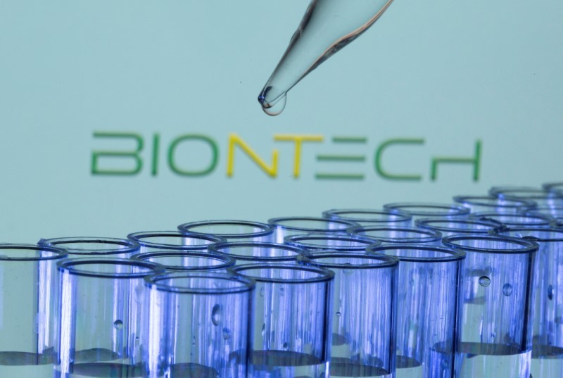 Test tubes are seen in front of a displayed Biontech logo in this illustration