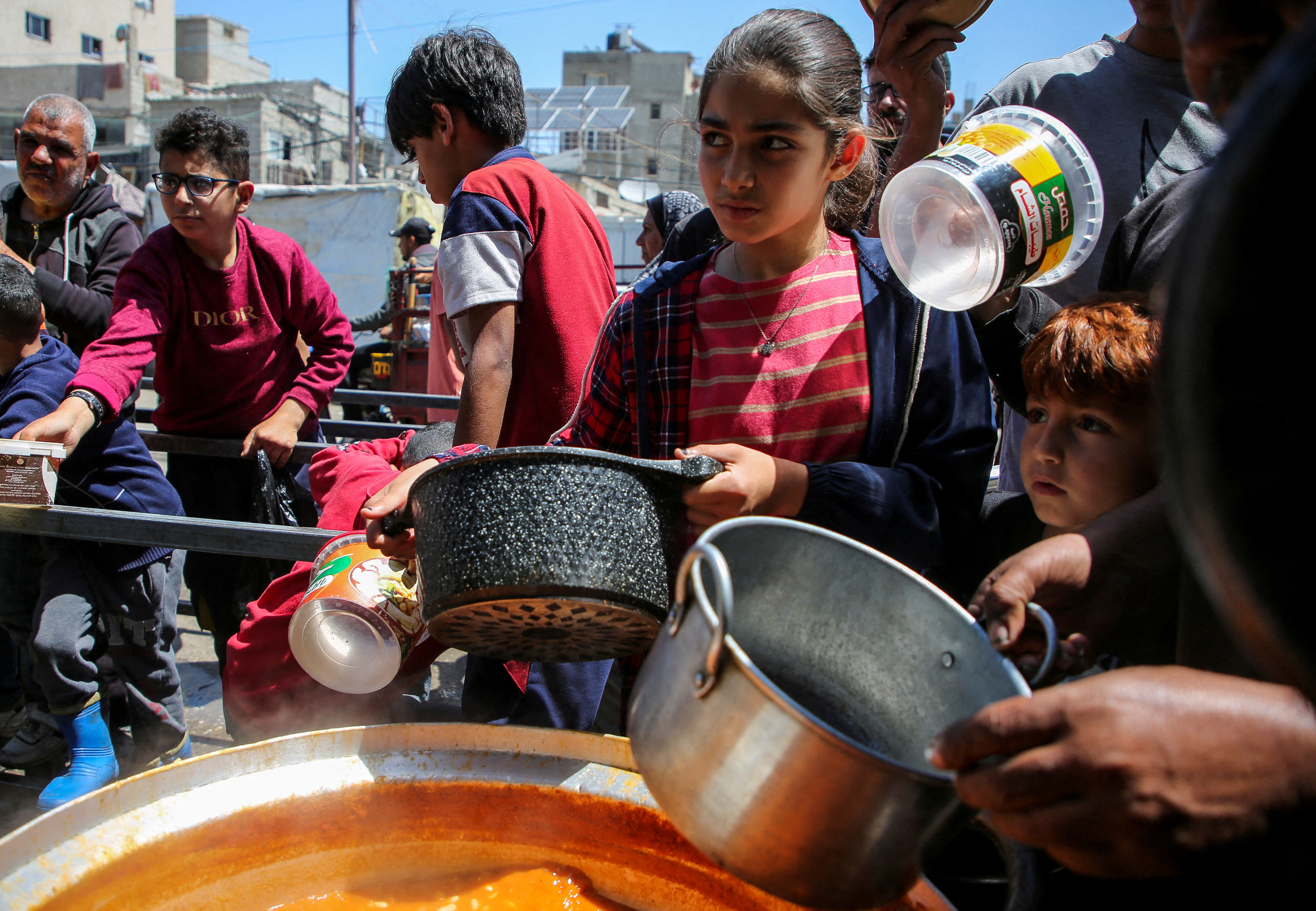 Palestinians wait to receive food cooked by a charity kitchen, in Rafah, in the southern Gaza Strip