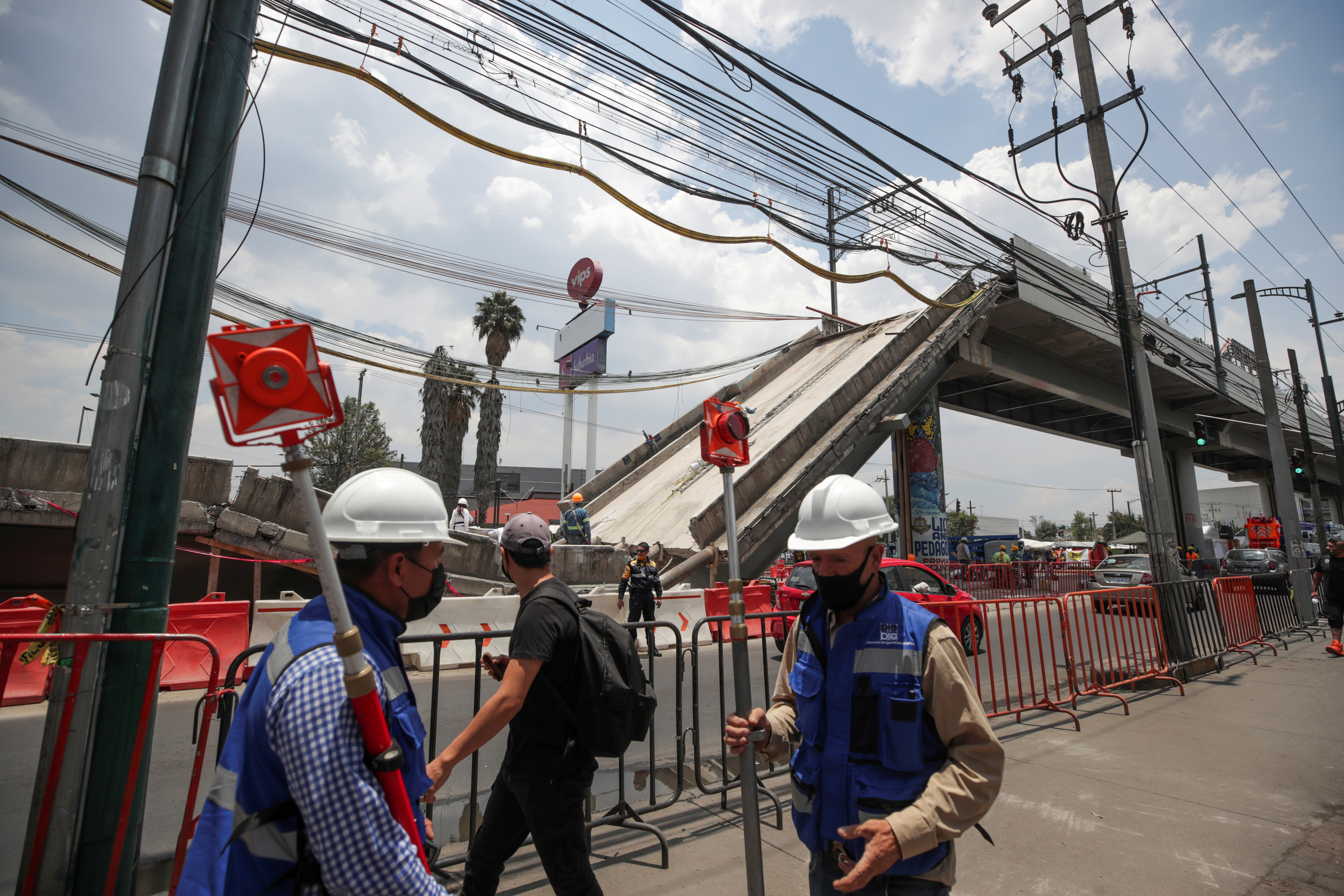 Employees work as part of the investigations in front of the site where an overpass for a metro partially collapsed with train cars on it, in Mexico City