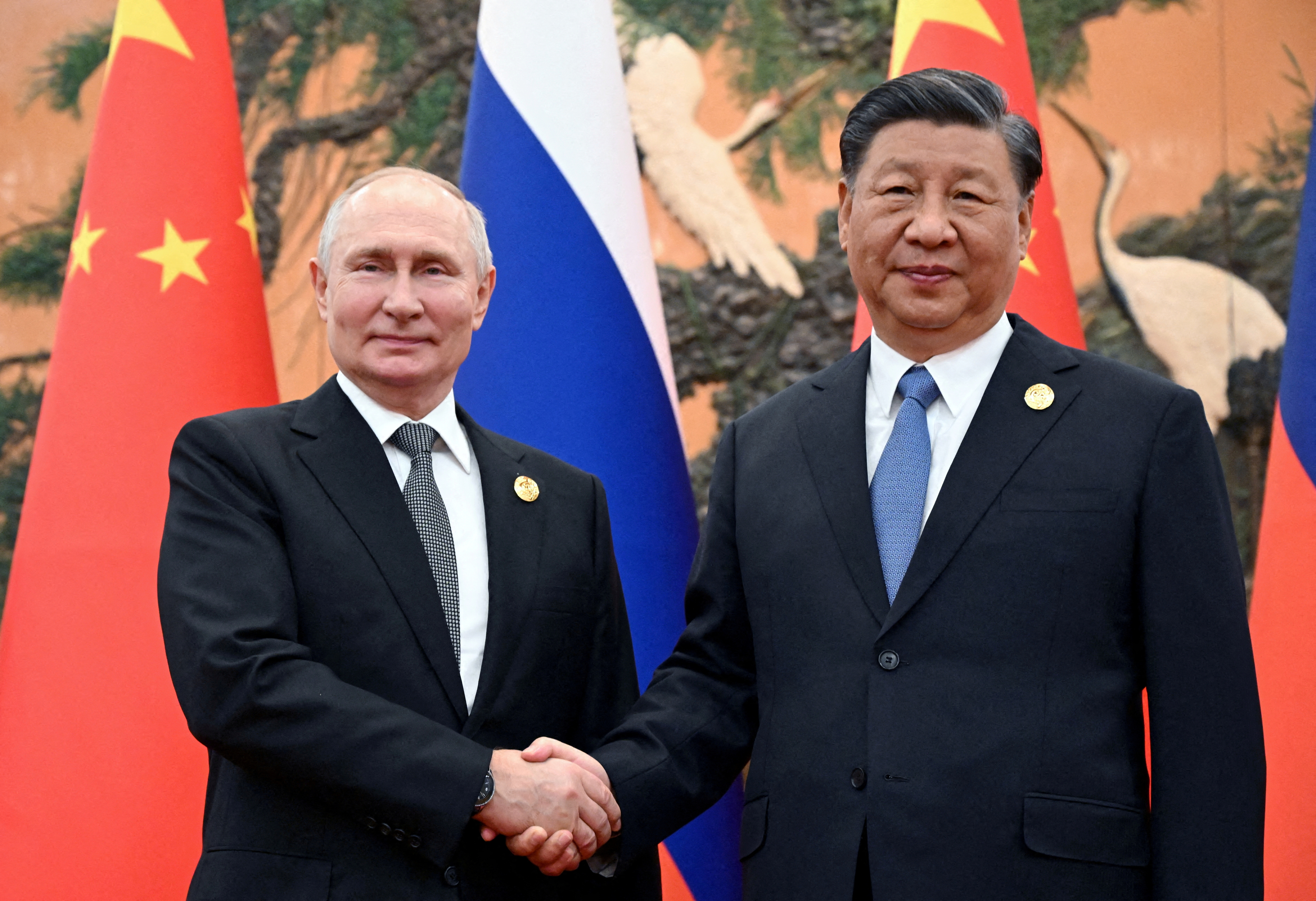 Russian President Vladimir Putin shakes hands with Chinese President Xi Jinping