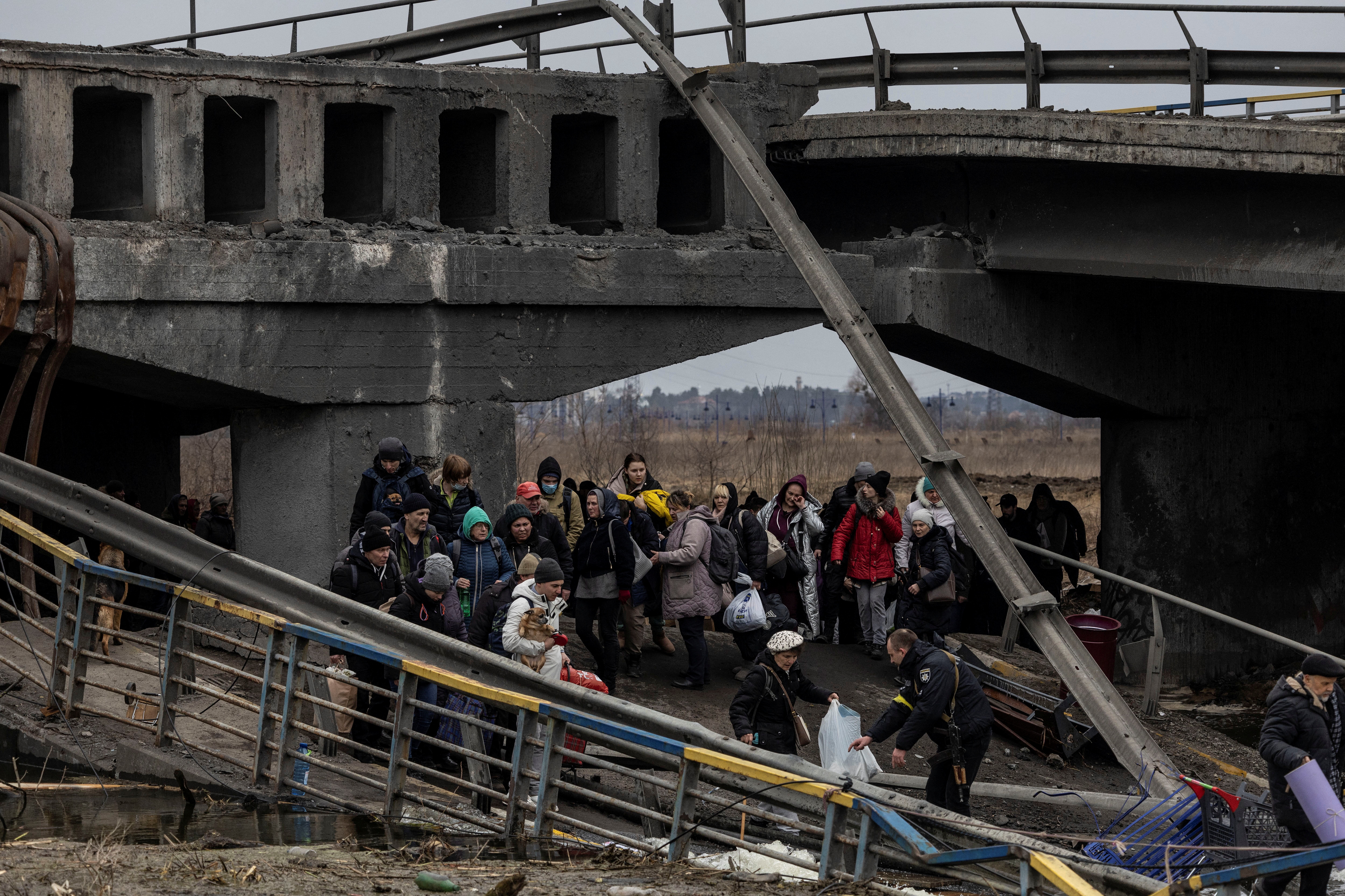 Local residents cross a destroyed bridge as they evacuate from the town of Irpin, after days of heavy shelling on the only escape route used by locals, while Russian troops advance towards the capital, in Irpin, near Kyiv
