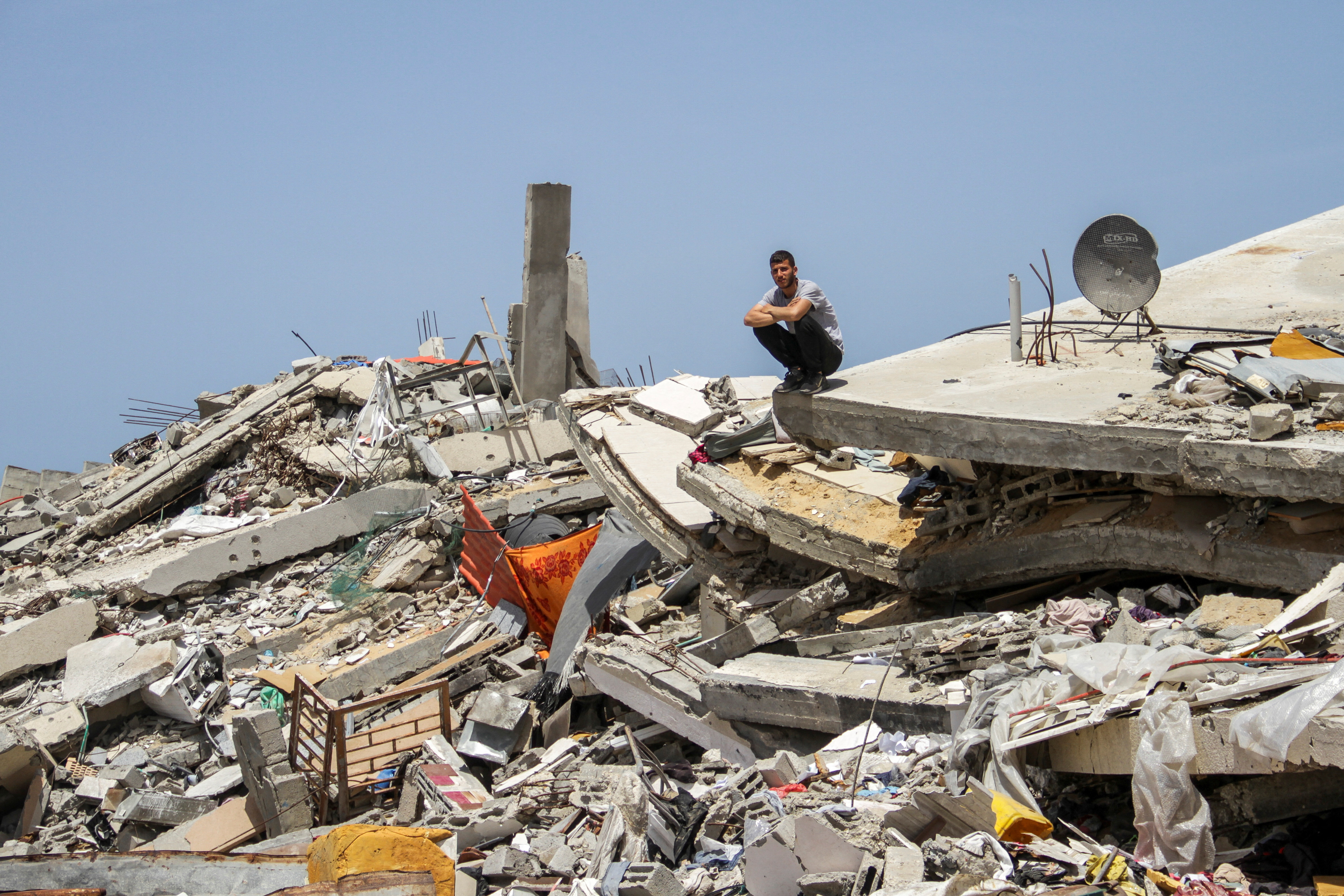 A Palestinian man sits on the rubble of a house destroyed by Israeli strikes, amid the ongoing conflict between Israel and Hamas, in the northern Gaza Strip
