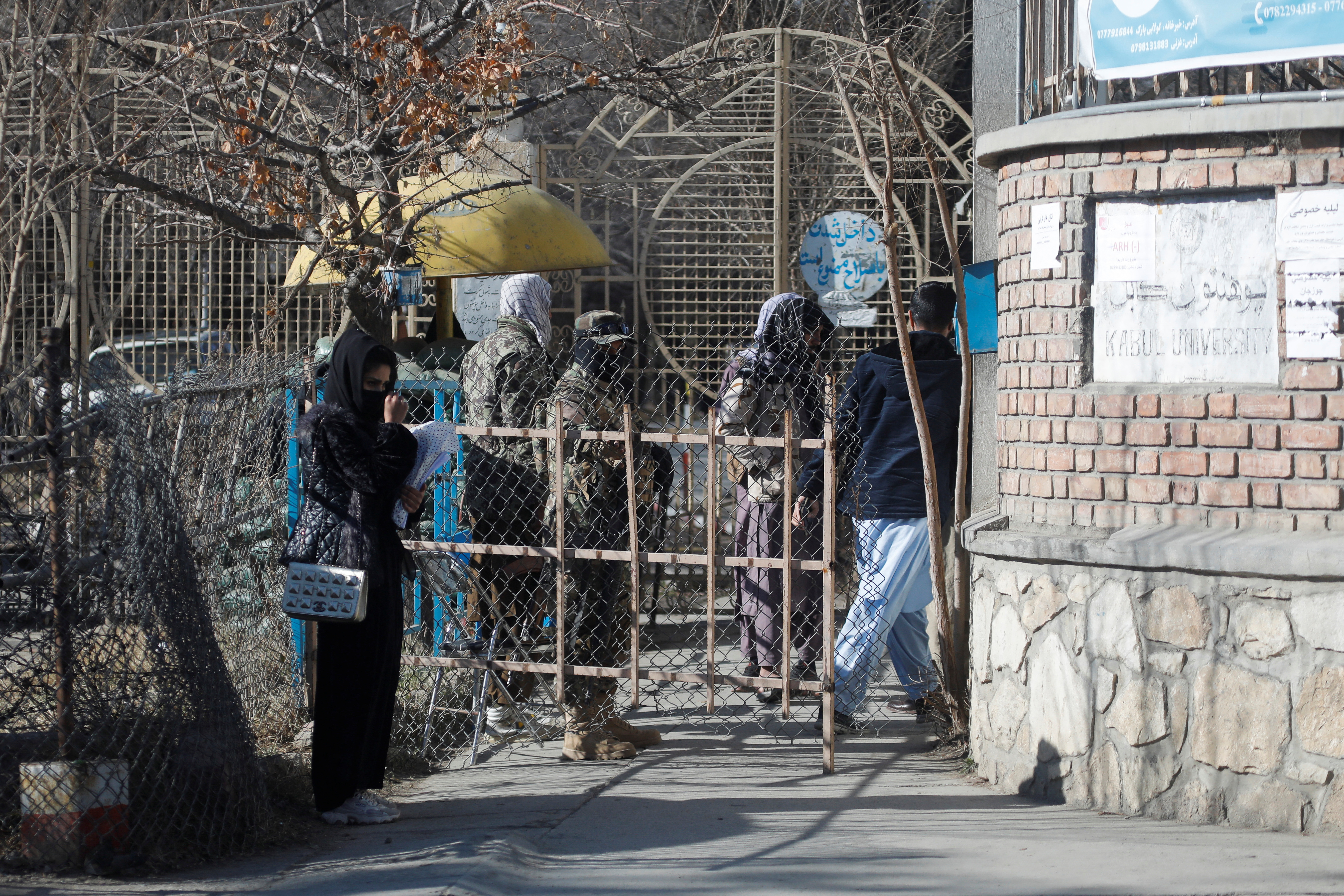 An Afghan female student stands in front of the entrance gate of Kabul University in Kabul