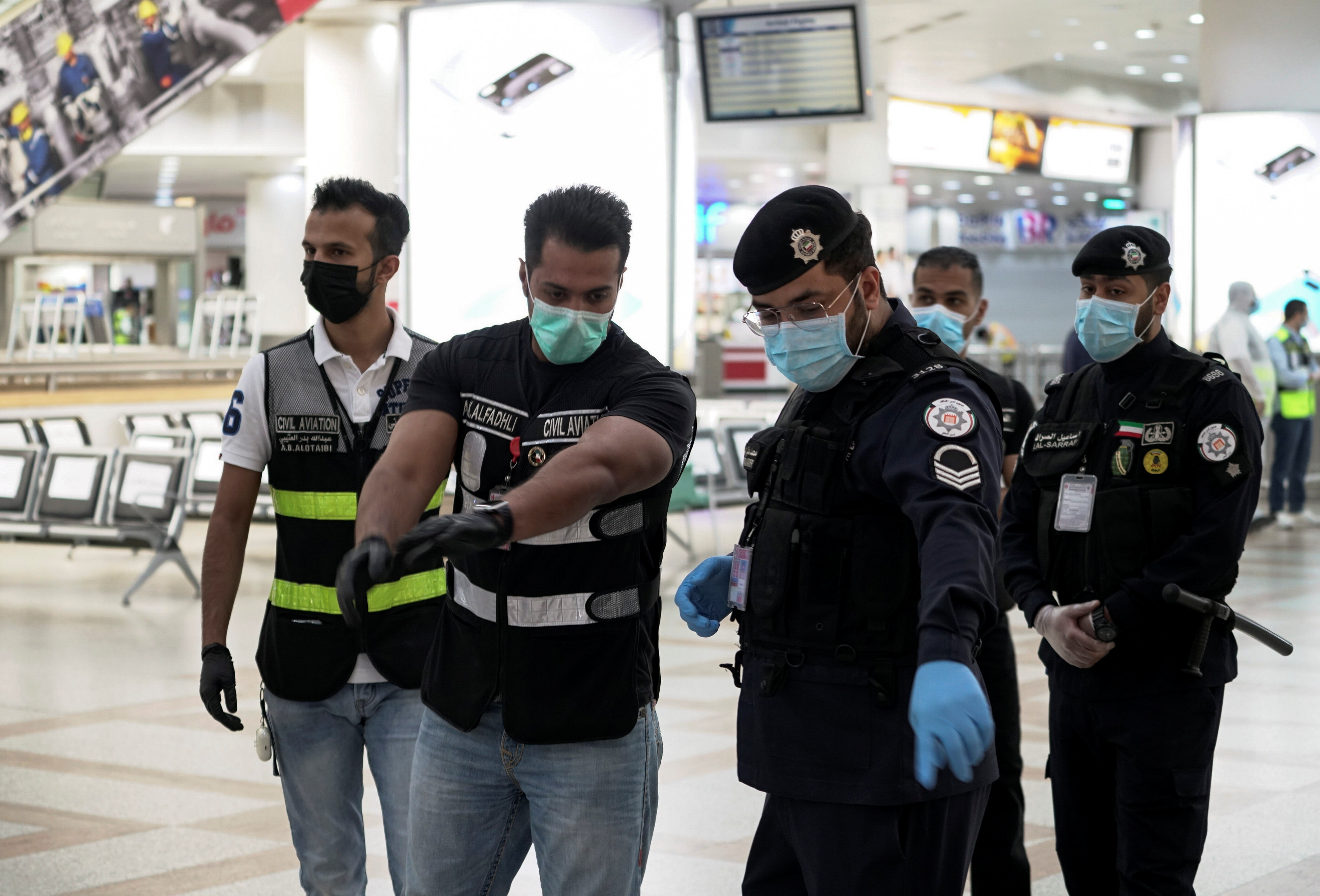 Police and civil aviation personnel wearing protective face masks work at the Kuwait Airport as the repatriation process of Kuwait citizens continues, in Kuwait City