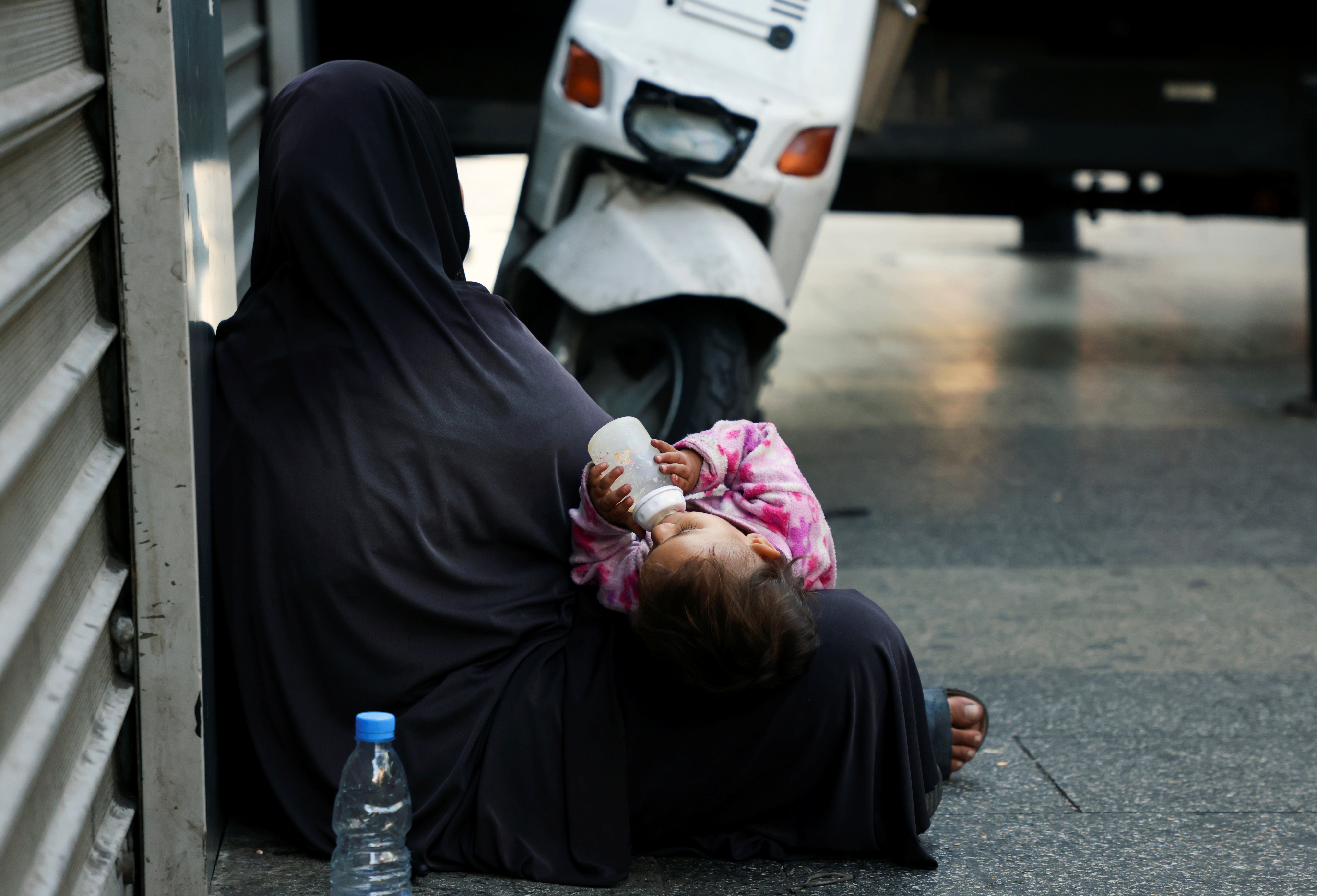 A woman begs with her child on a sidewalk in Beirut