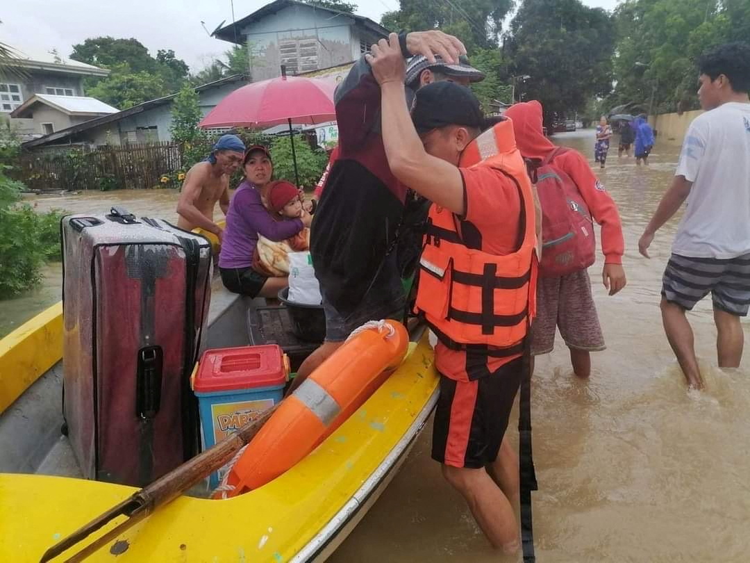 A rescuer assists a person on a rescue boat, after the tropical storm Megi hit, in Capiz Province