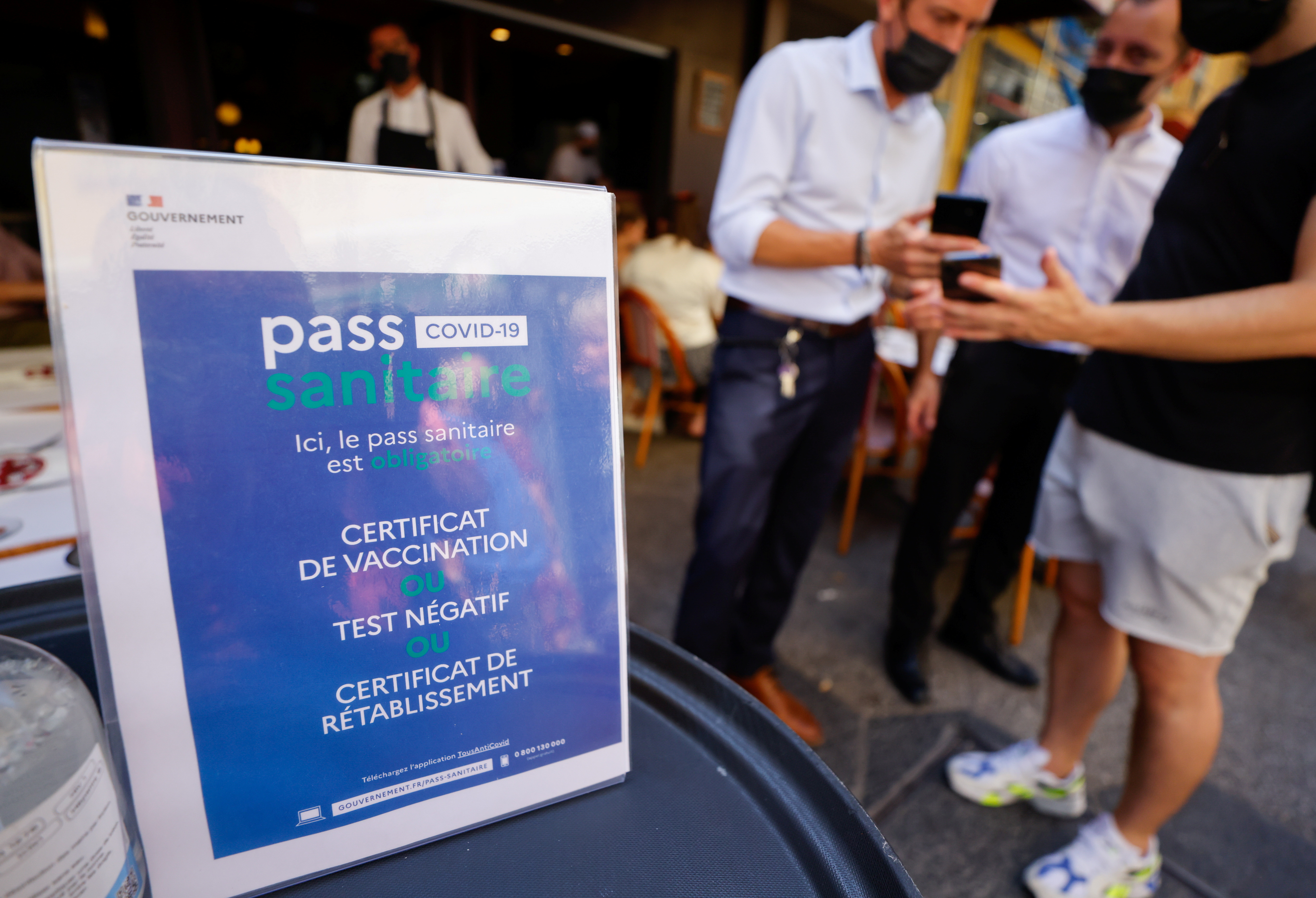 A man shows his COVID-19 health pass at a restaurant as France brings on tougher restrictions where a proof of immunity will now be required to access most public spaces and to travel by inter-city train, in Nice, France, August 9, 2021. REUTERS/Eric Gaillard
