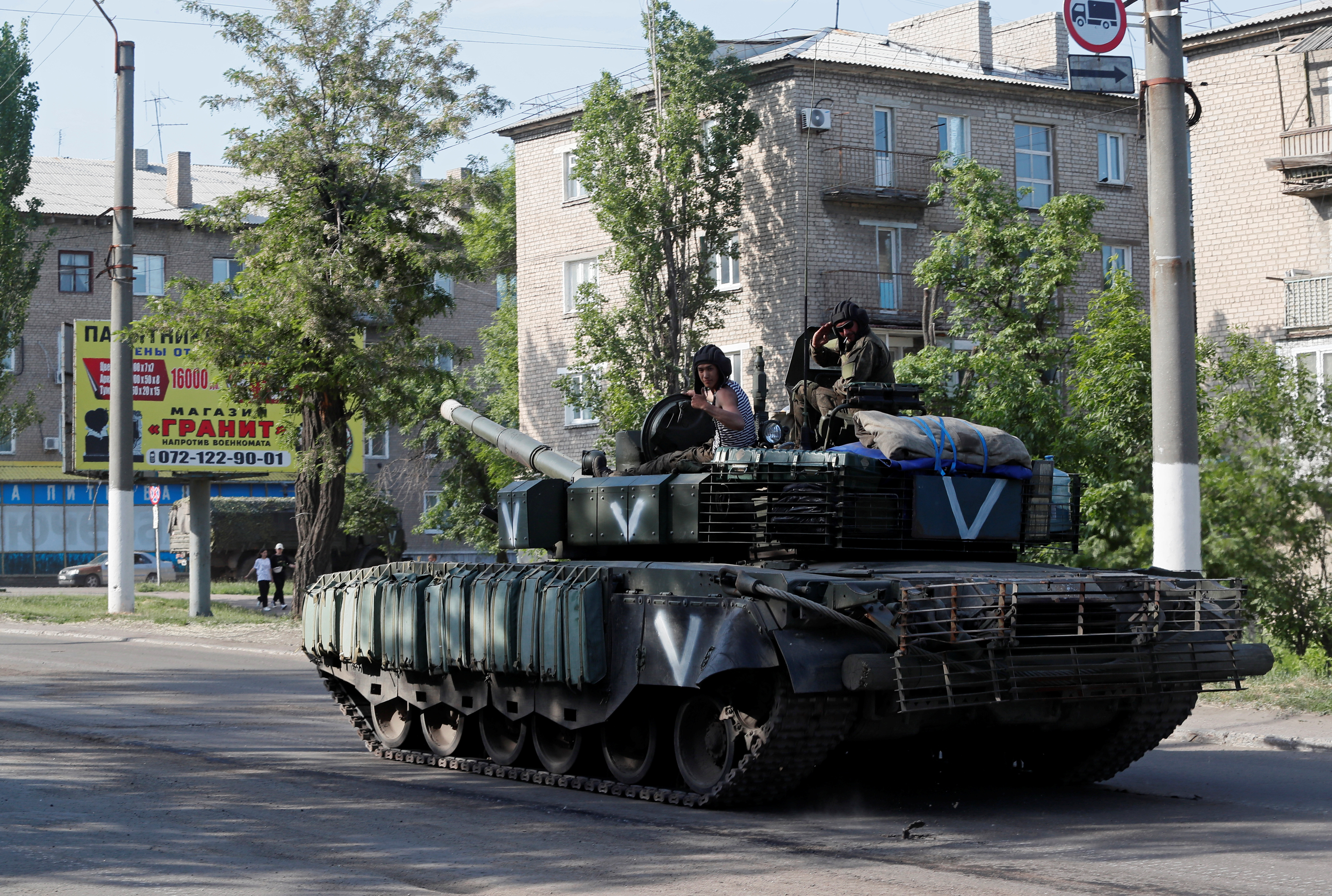 Service members of pro-Russian troops ride a tank in Popasna